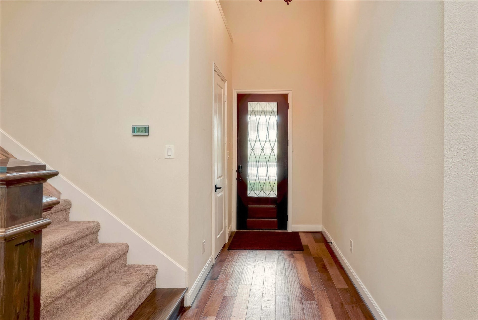 19 Herons Flight Place, Spring, TX 77389 Inviting entryway featuring a stylish glass-paneled front door, warm hardwood floors, and a carpeted staircase leading to the upper level.