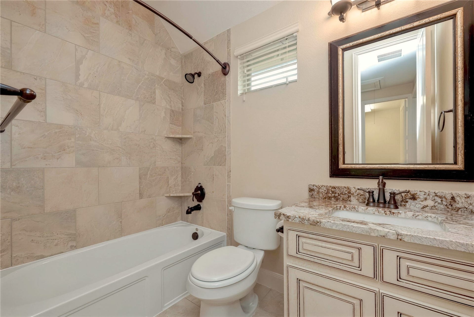 19 Herons Flight Place, Spring, TX 77389 Elegant bathroom featuring a luxurious granite countertop, classic vanity, and a beautifully tiled shower and tub combination.