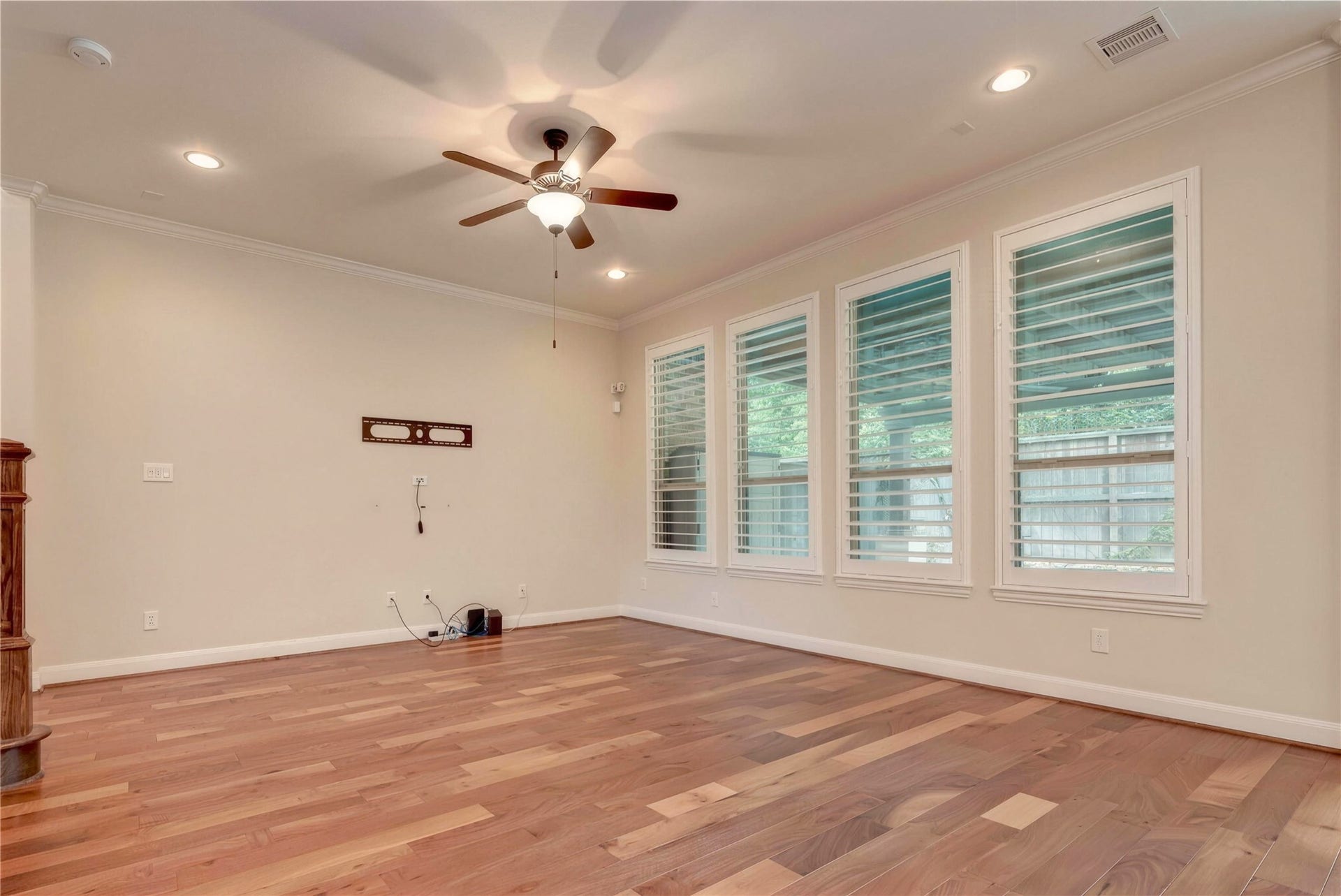 19 Herons Flight Place, Spring, TX 77389 Spacious living area with rich hardwood flooring, large windows with plantation shutters, and a ceiling fan for added comfort.