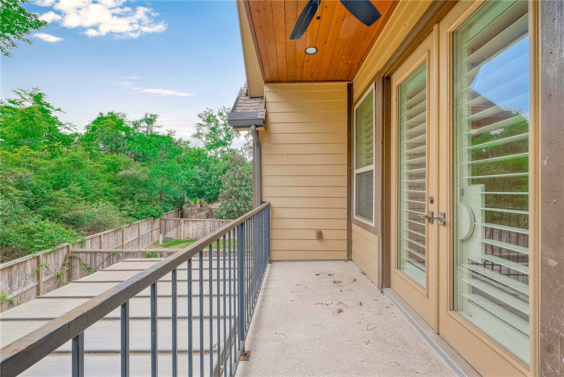19 Herons Flight Place, Spring, TX 77389 Charming balcony with French doors and a ceiling fan, offering a serene view of lush greenery for ultimate relaxation.