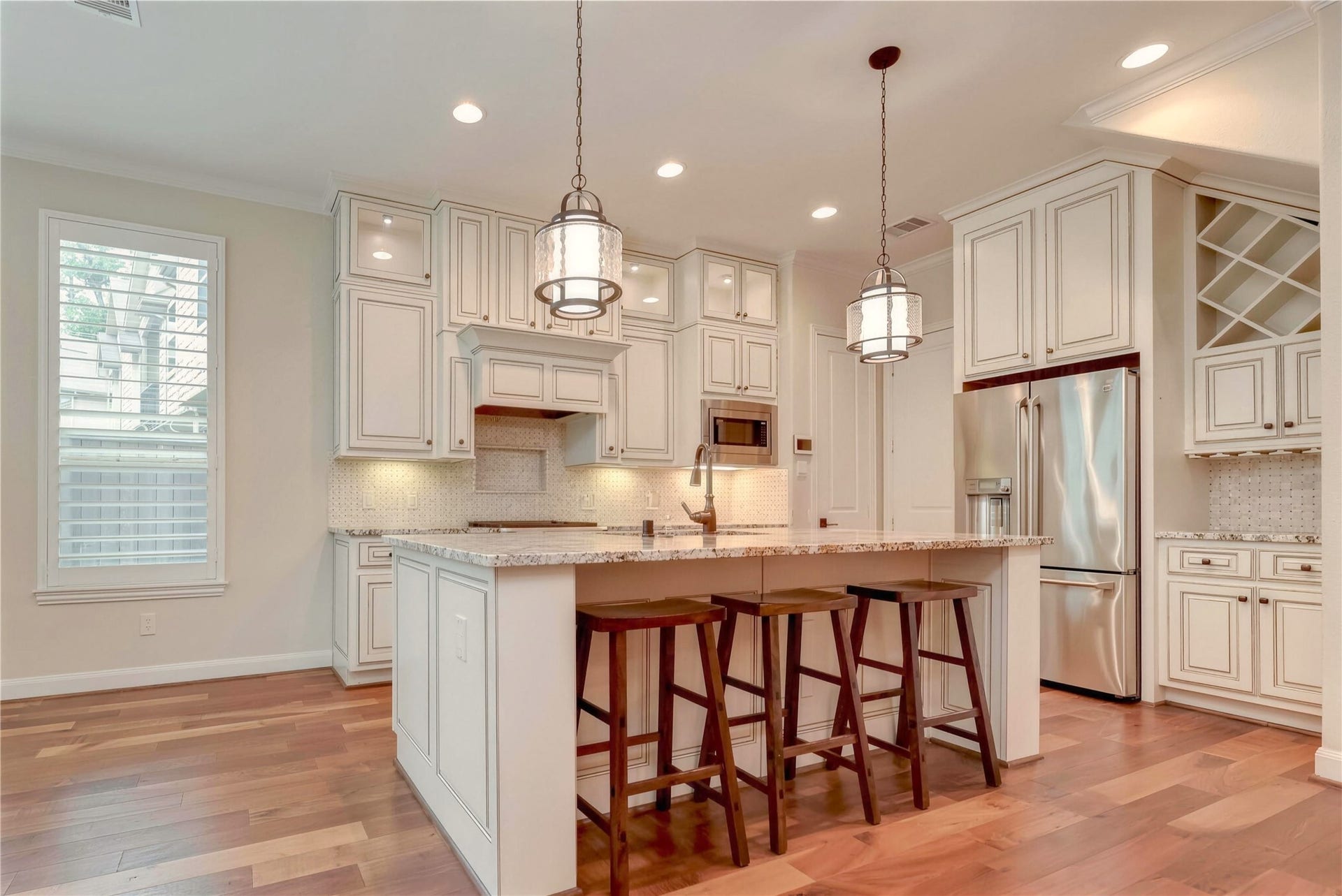 19 Herons Flight Place, Spring, TX 77389 Stunning kitchen with elegant white cabinetry, granite countertops, and a spacious island with seating. Stainless steel appliances and pendant lighting create a perfect blend of style and functionality.