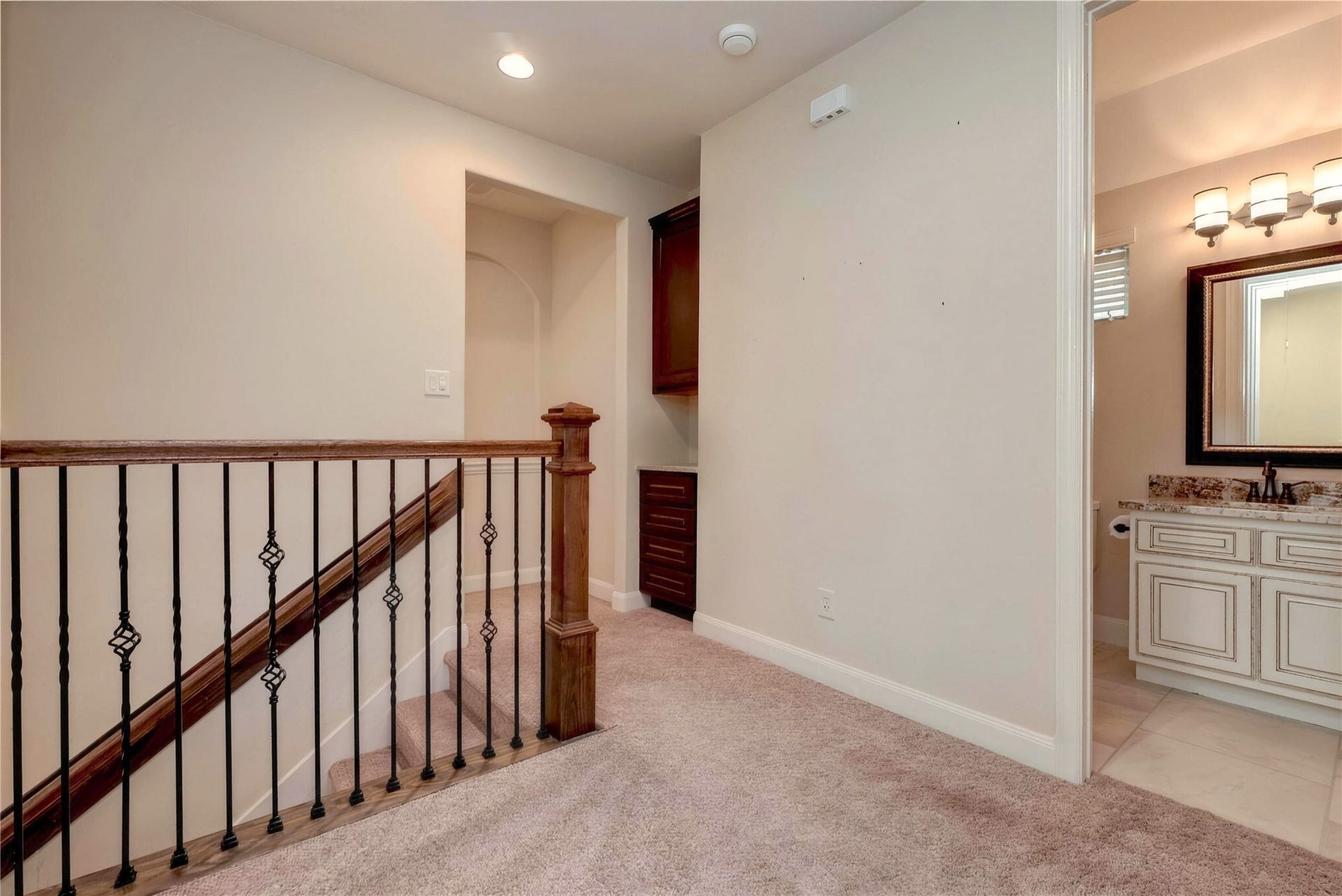 19 Herons Flight Place, Spring, TX 77389 Charming upstairs landing featuring a cozy carpeted space, elegant wooden railing, and convenient access to a well-appointed bathroom with stylish fixtures.