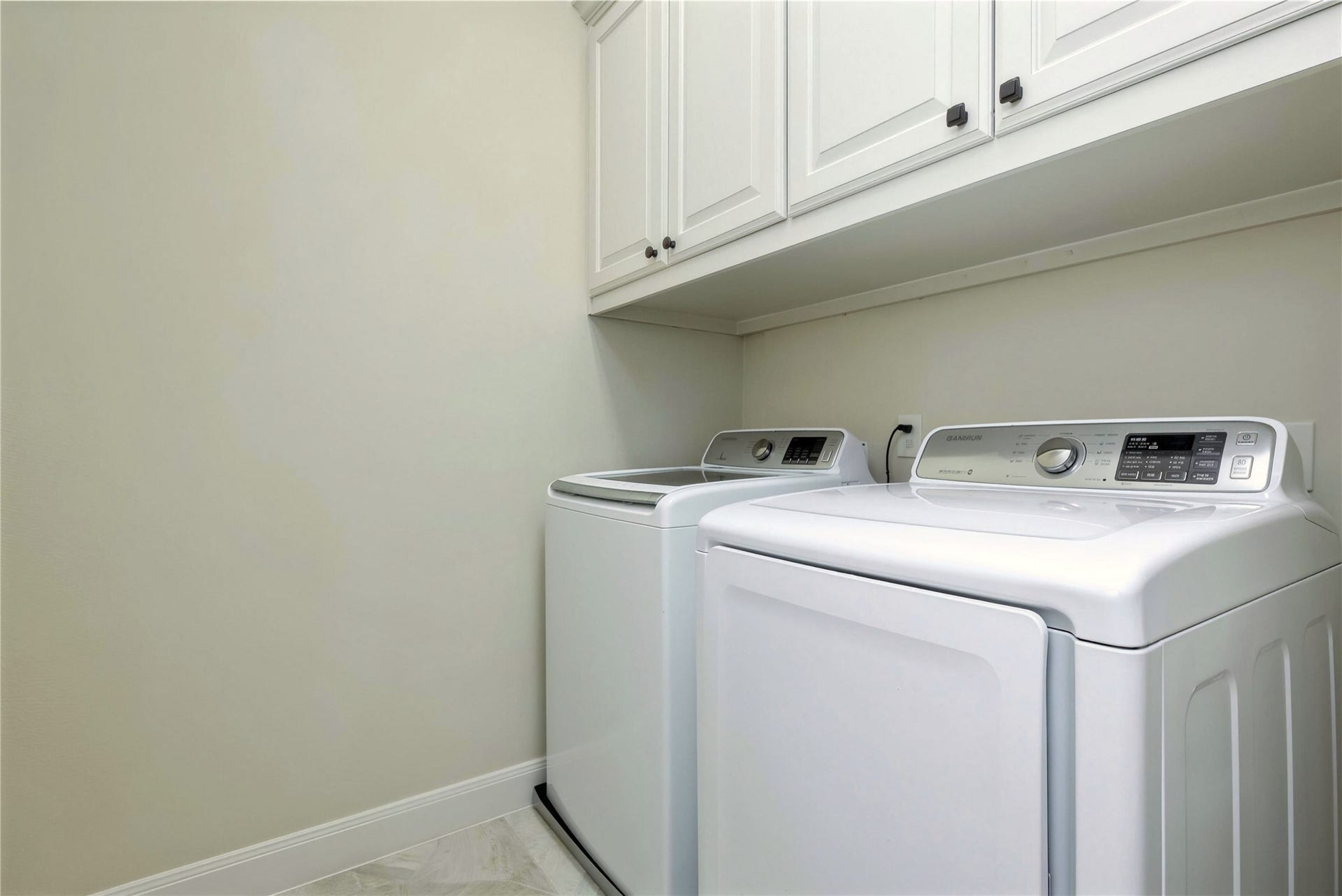 19 Herons Flight Place, Spring, TX 77389 Spacious laundry room featuring modern washer and dryer, ample cabinet storage, and sleek tile flooring.