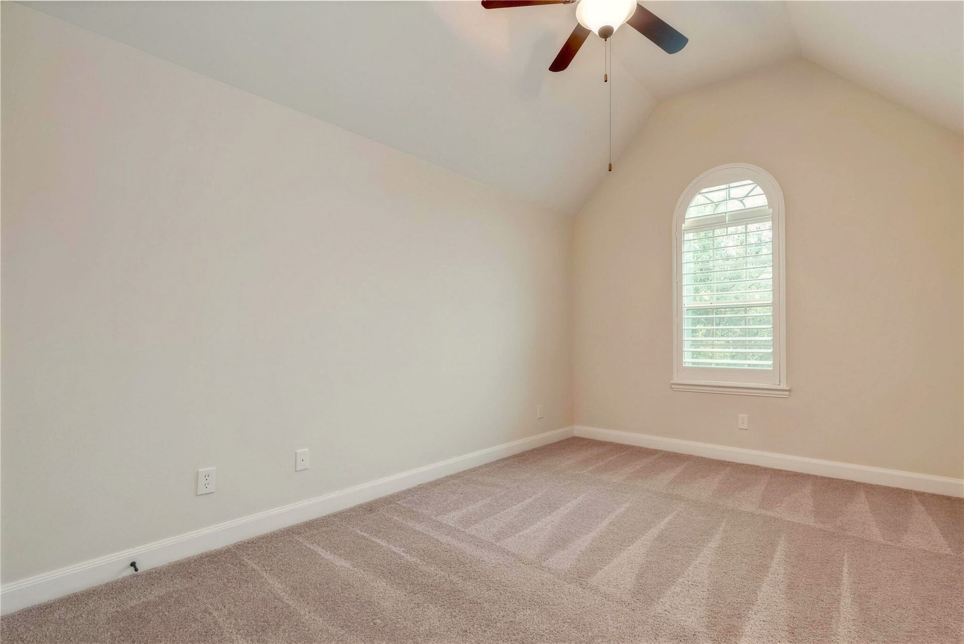 19 Herons Flight Place, Spring, TX 77389 Bright and airy bedroom with vaulted ceiling, neutral carpeting, and a charming arched window offering plenty of natural light.