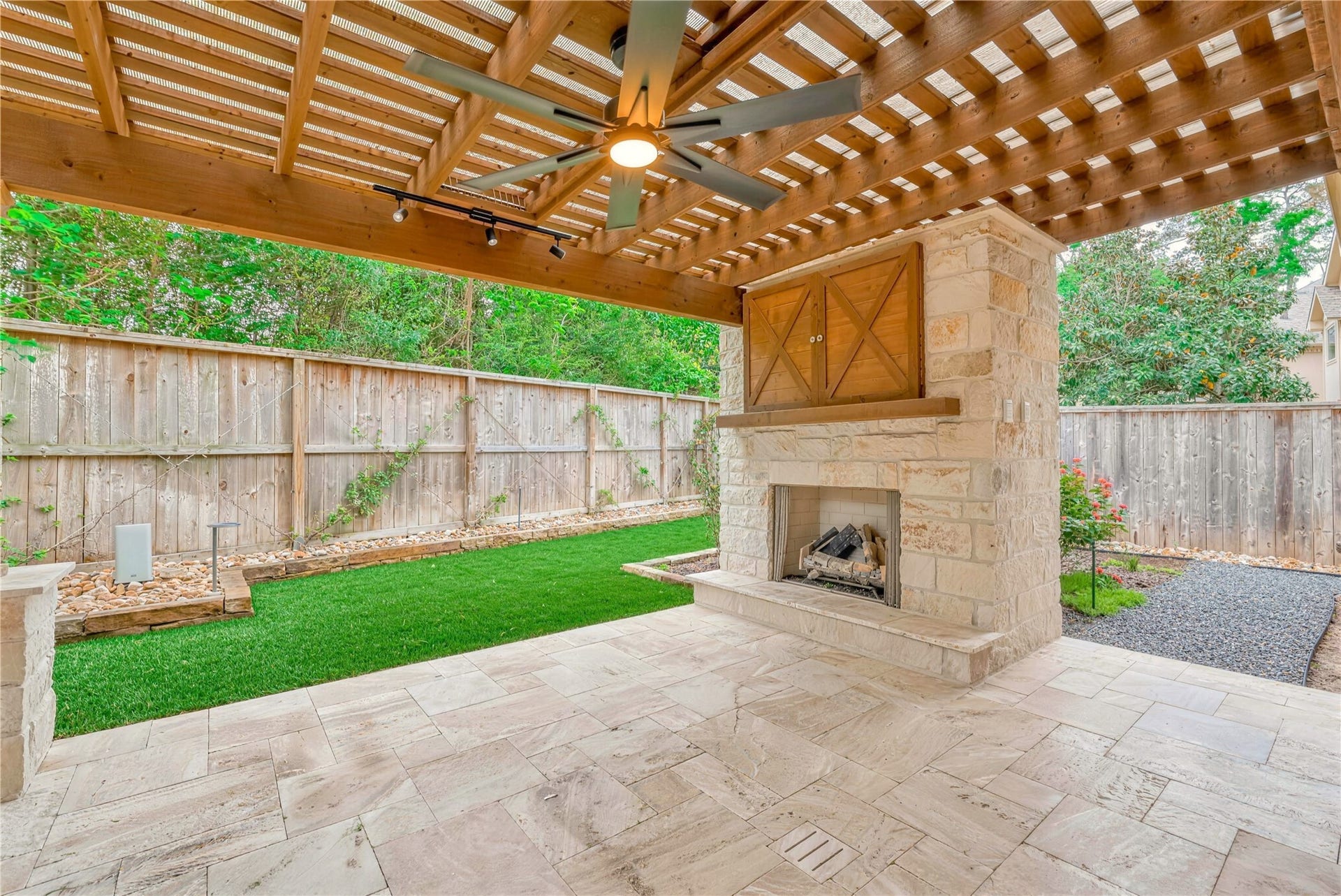 19 Herons Flight Place, Spring, TX 77389 Charming outdoor patio featuring a rustic pergola, cozy stone fireplace, and beautifully landscaped garden.