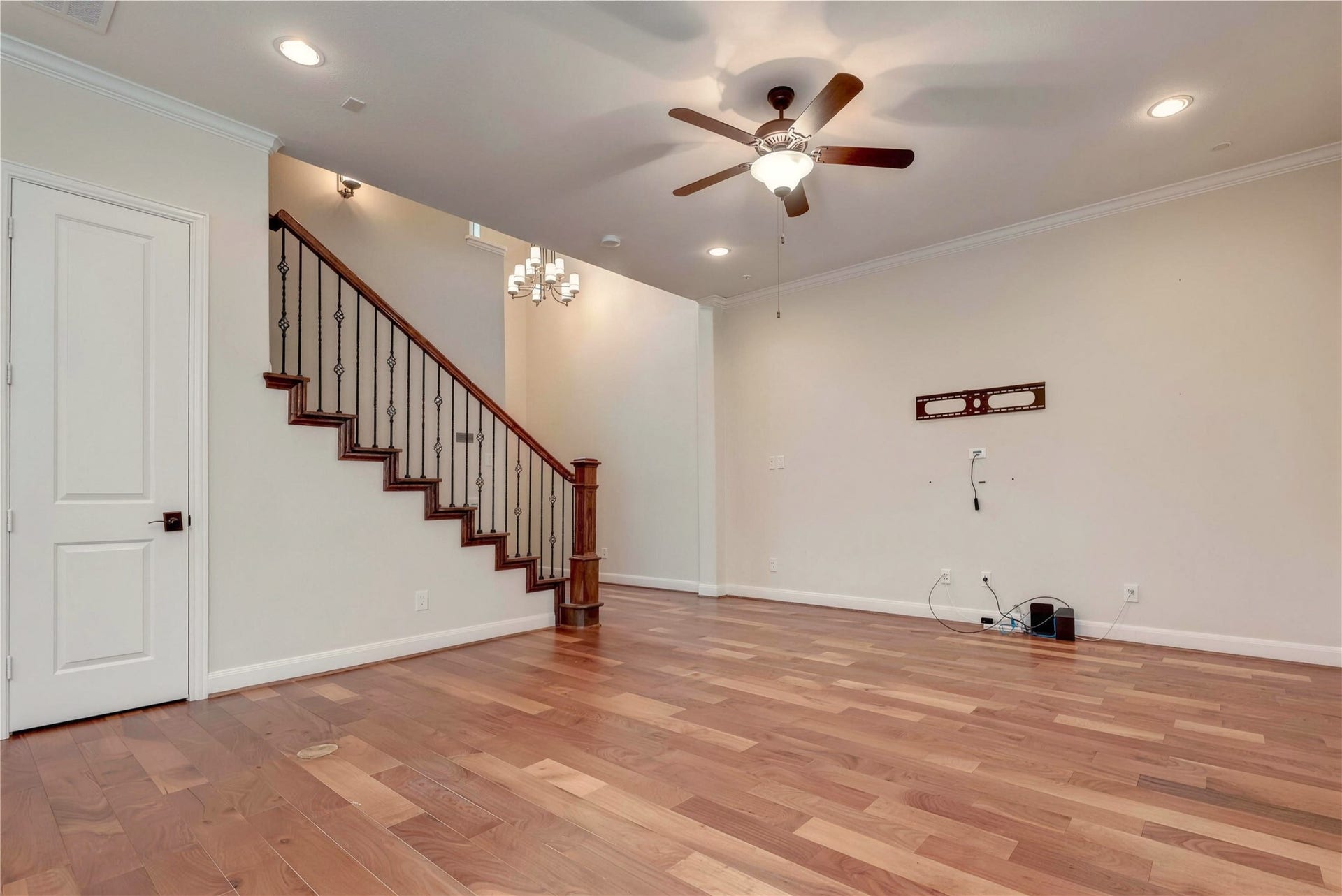 19 Herons Flight Place, Spring, TX 77389 Spacious living area featuring elegant hardwood floors, a ceiling fan, and a stylish staircase with wrought iron balusters.