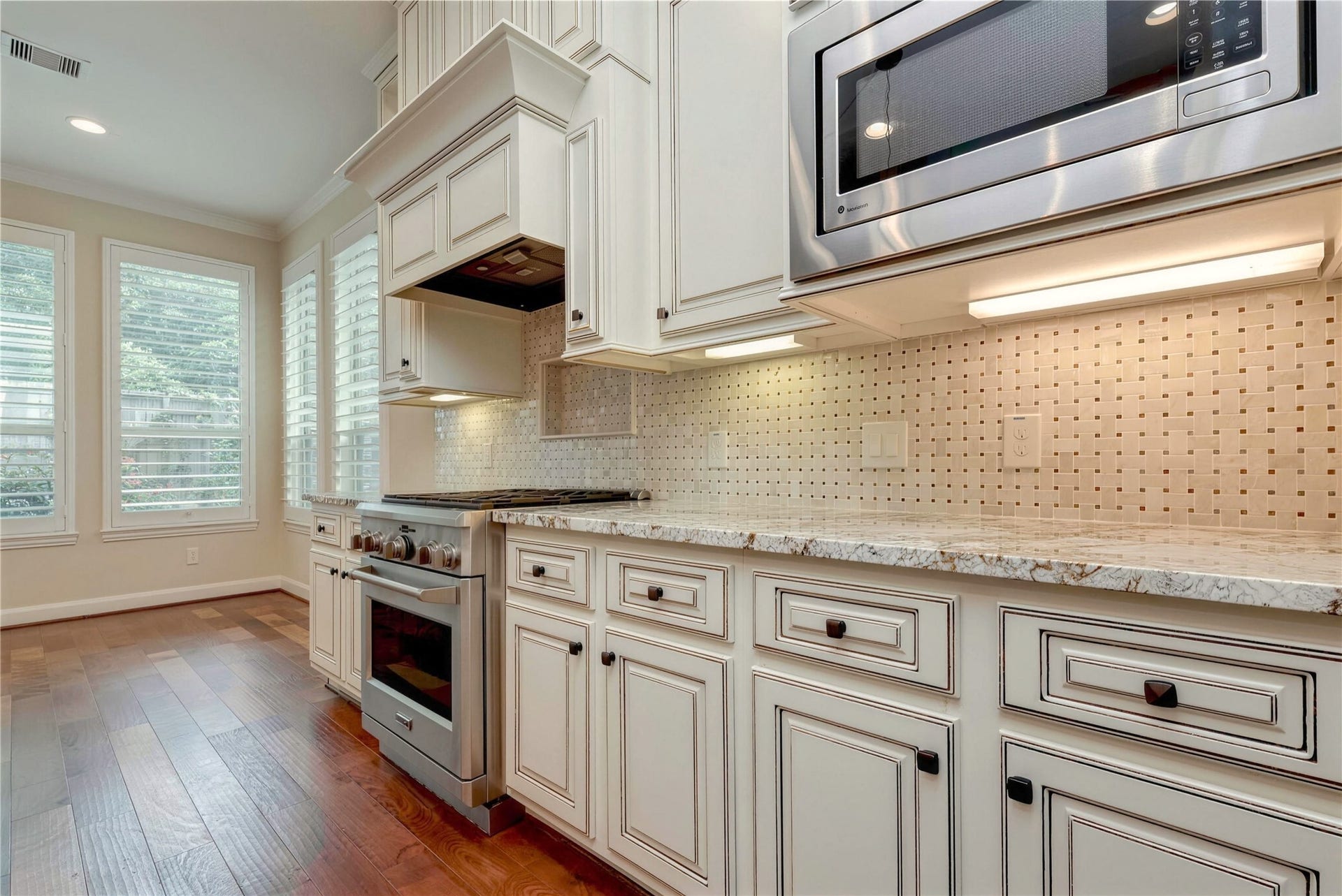 19 Herons Flight Place, Spring, TX 77389 Elegant kitchen with custom cabinetry, granite countertops, and stainless steel appliances, bathed in natural light from large windows.