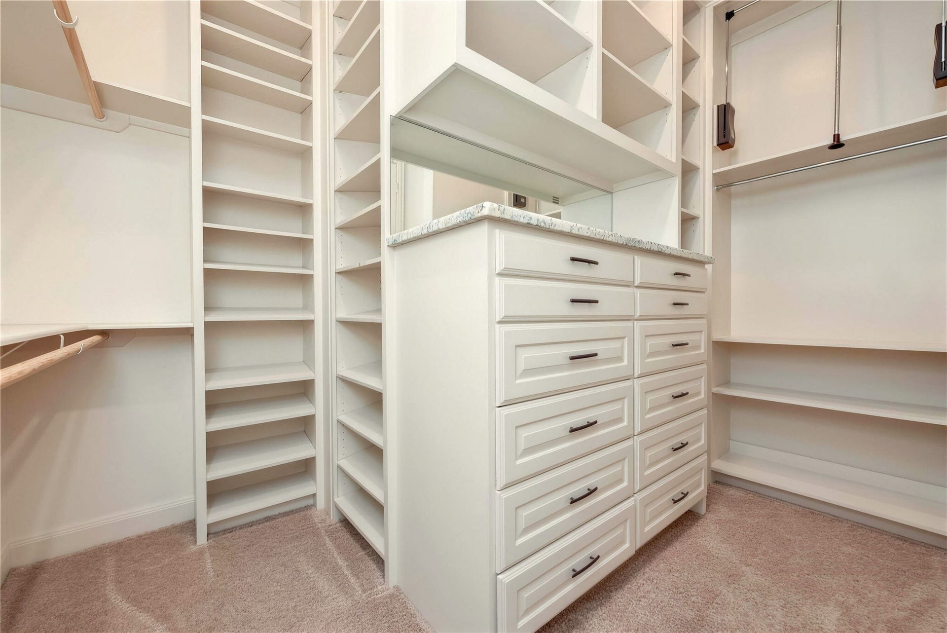 19 Herons Flight Place, Spring, TX 77389 Spacious walk-in closet featuring custom built-in shelving, ample drawer storage, and a sleek countertop for organization and convenience.