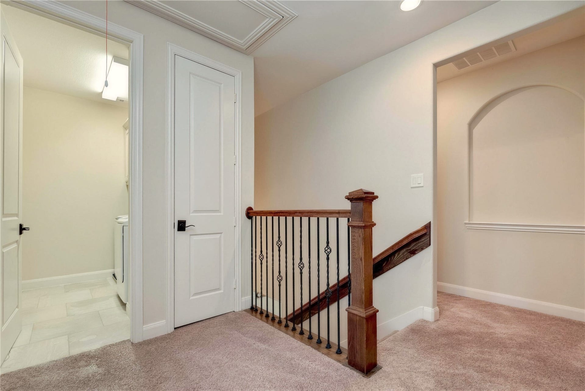 19 Herons Flight Place, Spring, TX 77389 Charming hallway with plush carpeting, elegant wooden banister, and convenient access to a laundry room, perfect for seamless living.