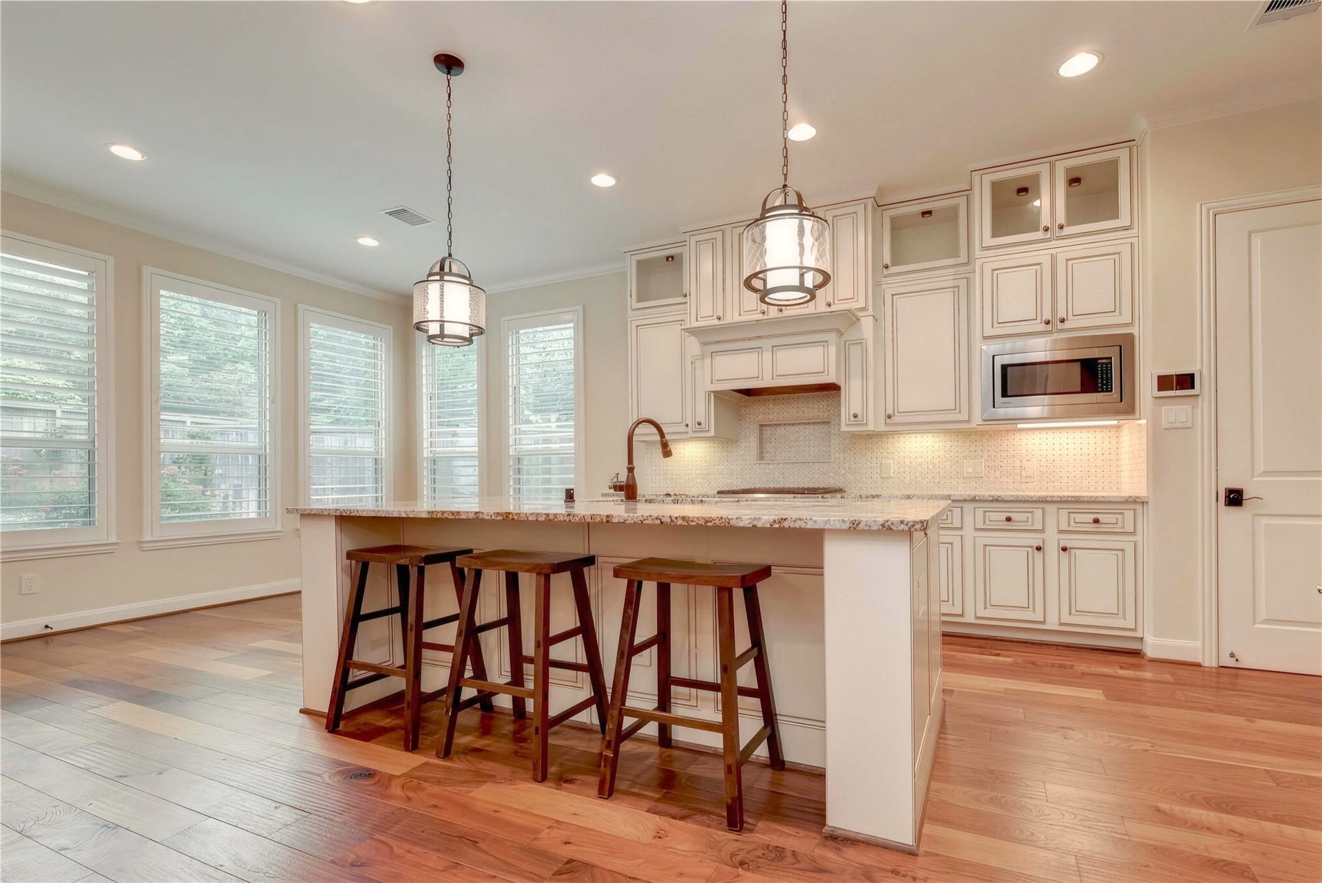 19 Herons Flight Place, Spring, TX 77389 Bright and inviting kitchen with elegant cabinetry, a spacious island with seating, and large windows providing ample natural light.