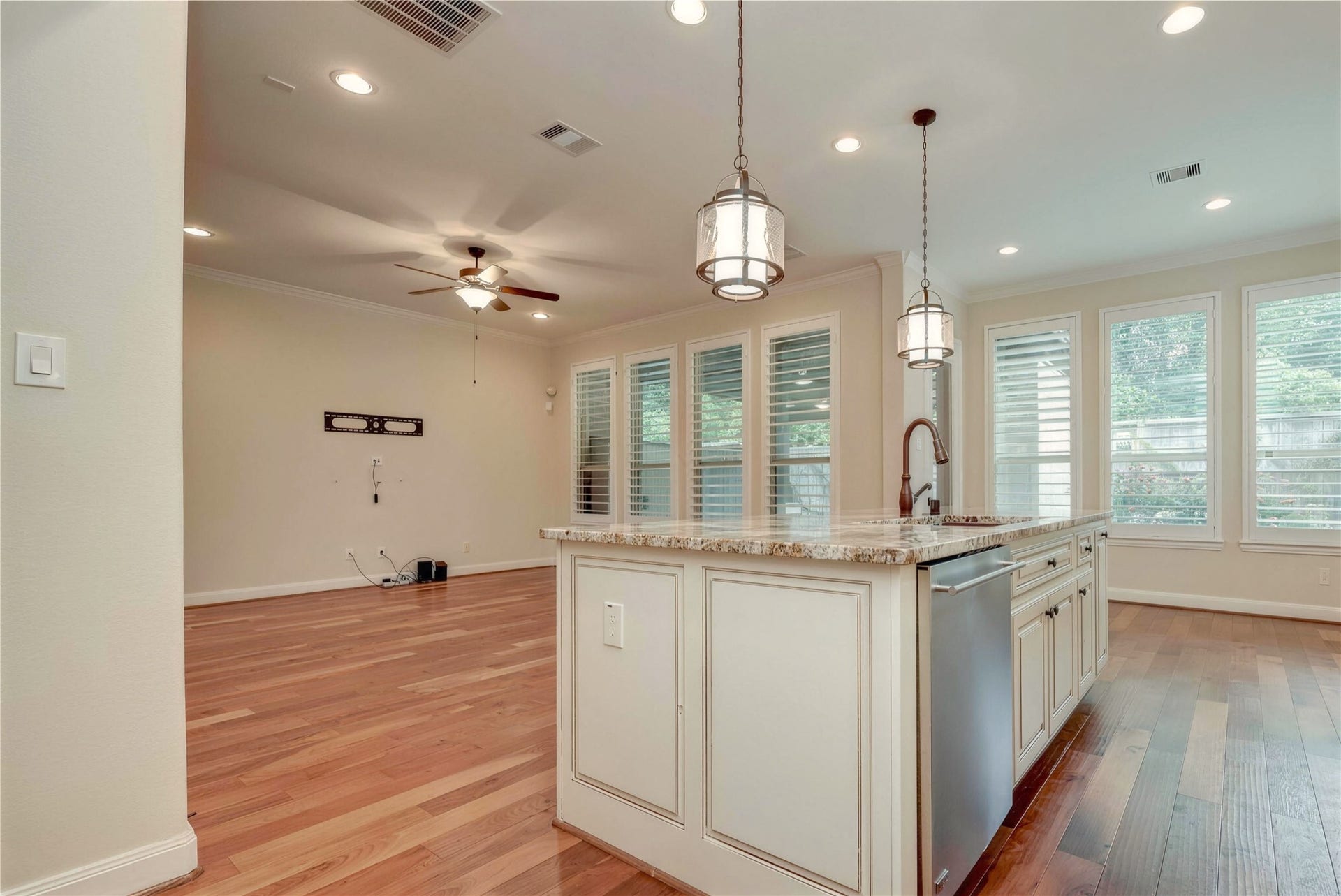 19 Herons Flight Place, Spring, TX 77389 Spacious open-concept living area with elegant hardwood floors, featuring a modern kitchen island with granite countertops and stylish pendant lighting, complemented by large windows that fill the space with natural light.