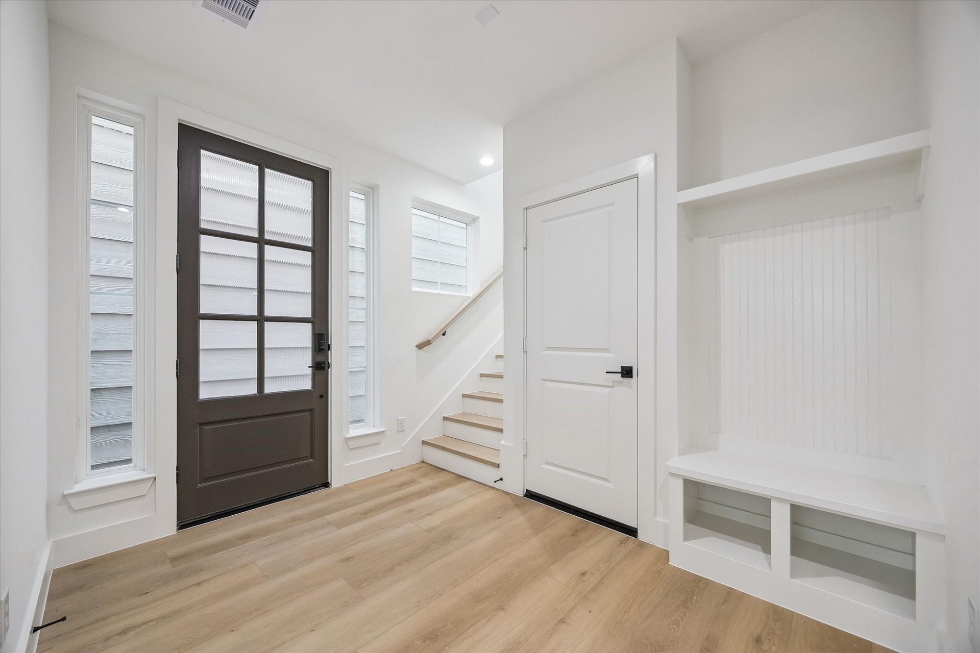 Welcoming entry with tall door, stair detail, and built-in drop zone