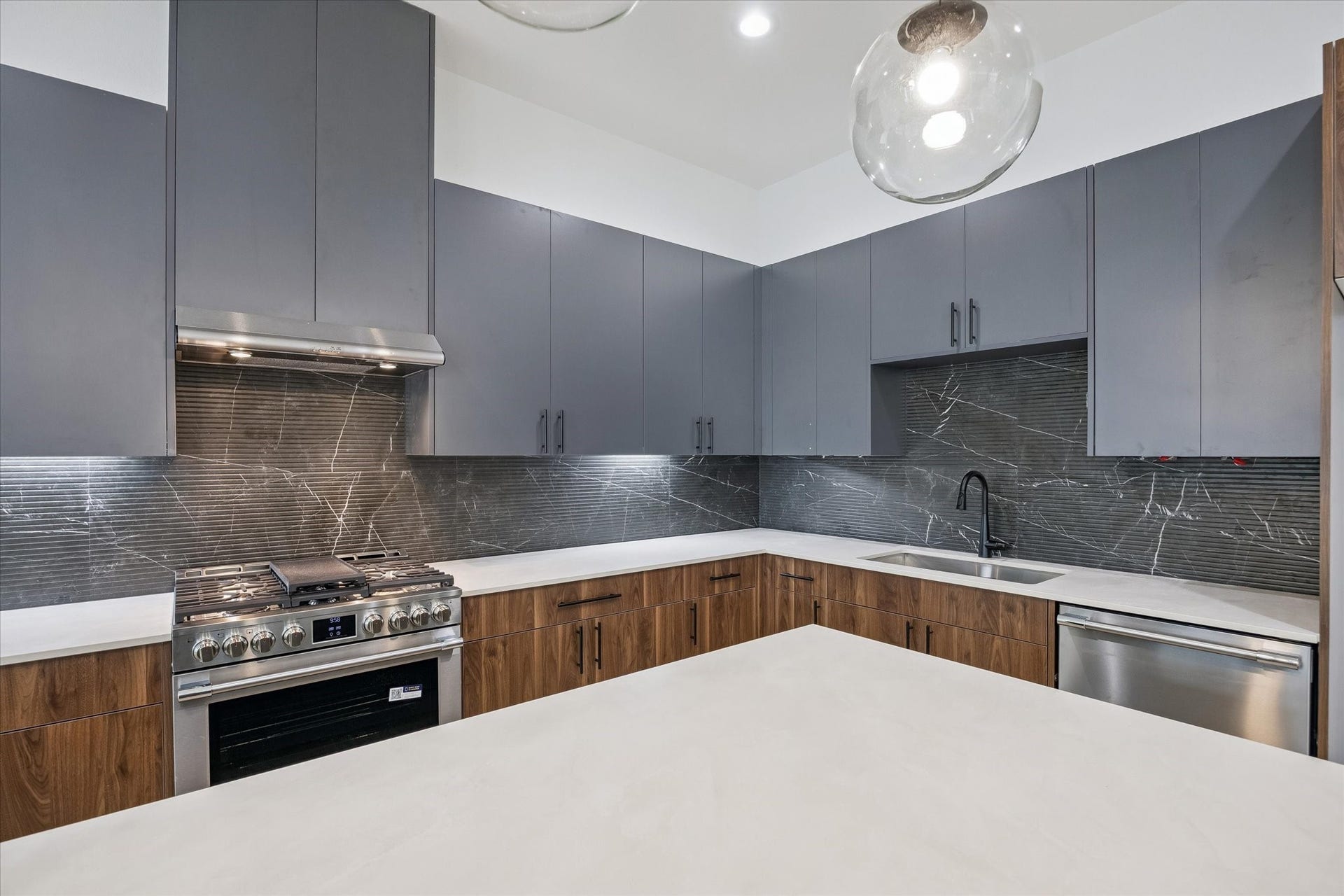 Gas range, vent hood, and backsplash detail for a refined kitchen finish