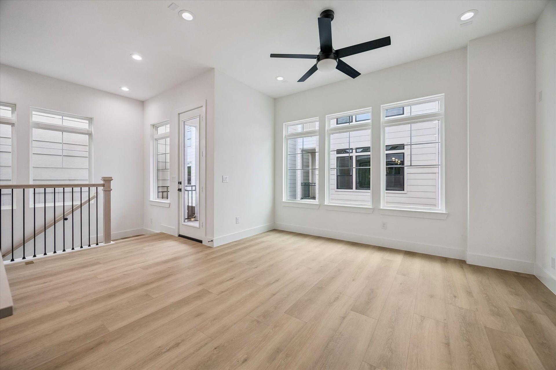 Comfortable living area with ceiling fan, windows, and warm flooring