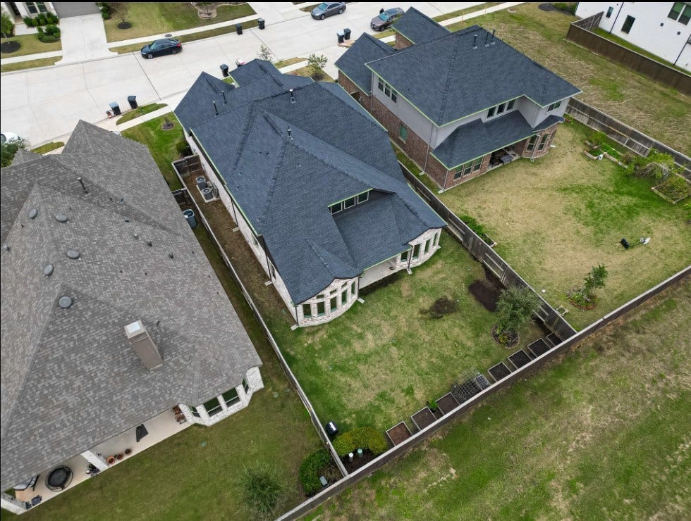 This aerial perspective showcases the impressive size of the backyard and highlights the covered patio's connection to the home. The expansive outdoor space offers room to grow, play, and entertain while providing a clear sense of the property's scale.