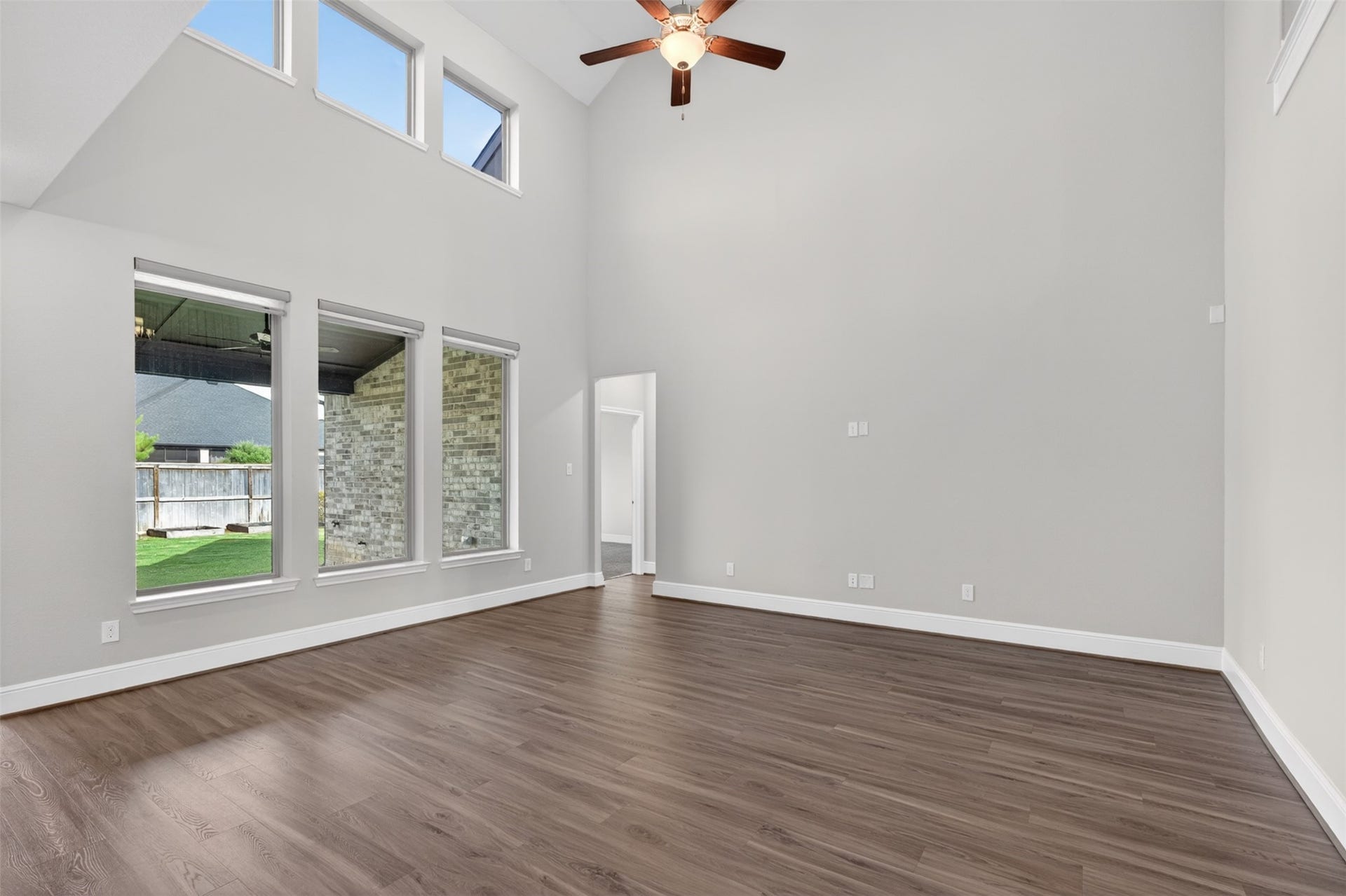 The family room serves as the heart of the home, where soaring ceilings and a dramatic wall of windows create a bright and welcoming atmosphere. Natural light pours into the space while backyard views provide a beautiful backdrop for everyday living.