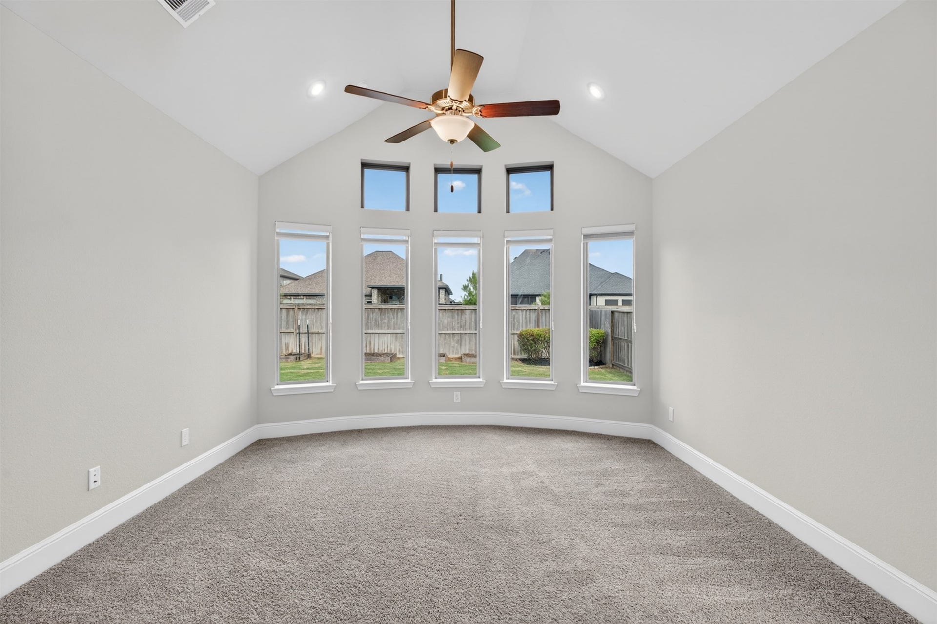 Privately situated on the main floor, the primary suite offers a peaceful retreat designed for comfort and relaxation. Vaulted ceilings and expansive windows create an airy, light-filled atmosphere while providing tranquil views of the backyard.