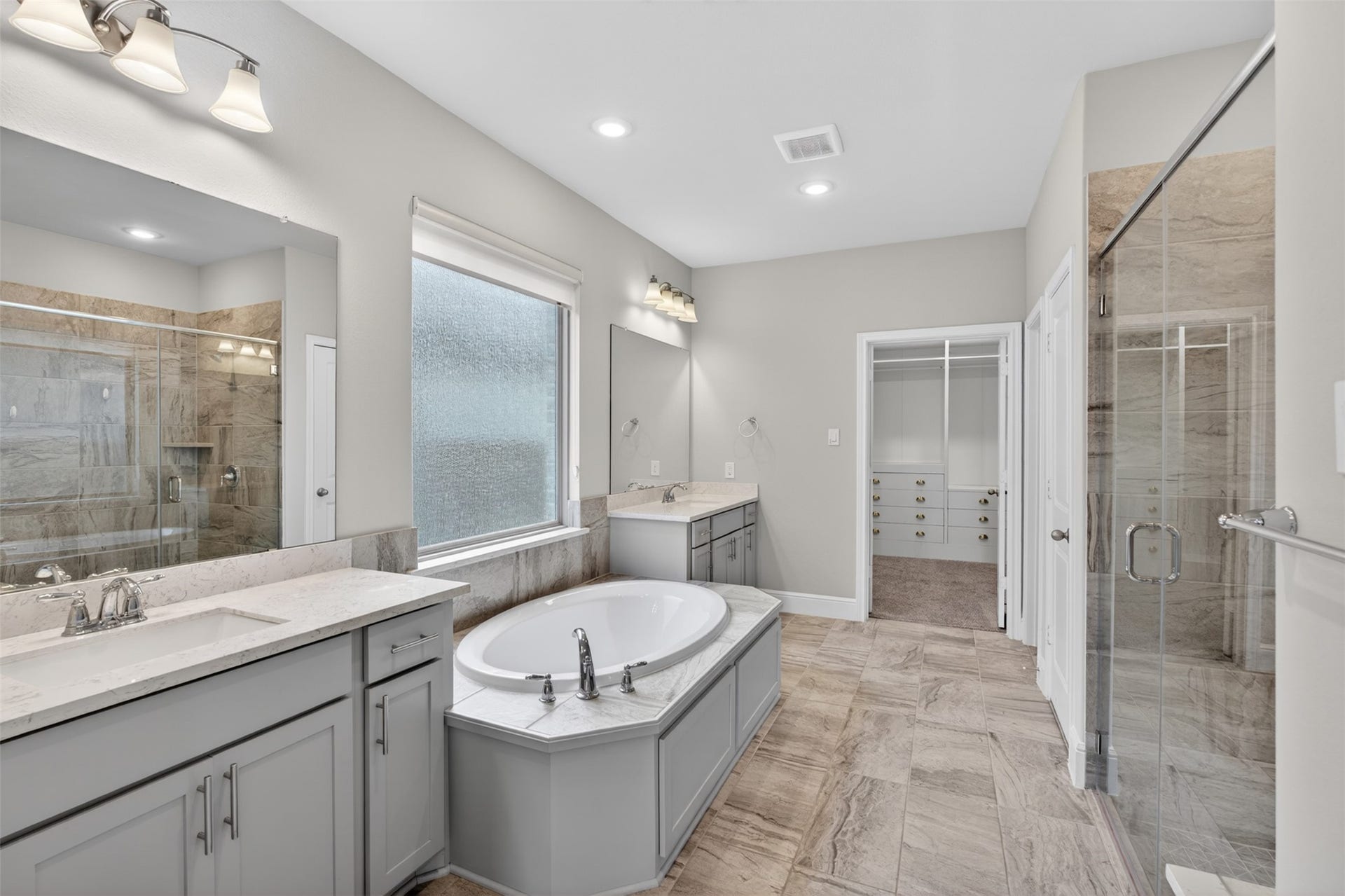 Designed with relaxation in mind, the luxurious primary bathroom offers dual vanities, a spacious glass-enclosed walk-in shower, and a soaking tub that invites you to slow down and unwind.