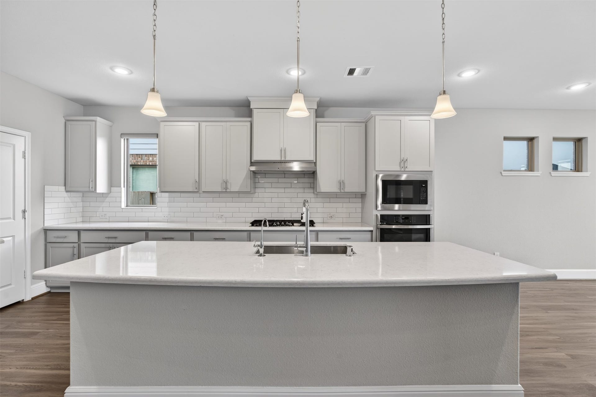 Crisp white cabinetry, pendant lighting and stainless steel appliacances add a fresh, timeless feel, while the extended breakfast bar anchors the space.