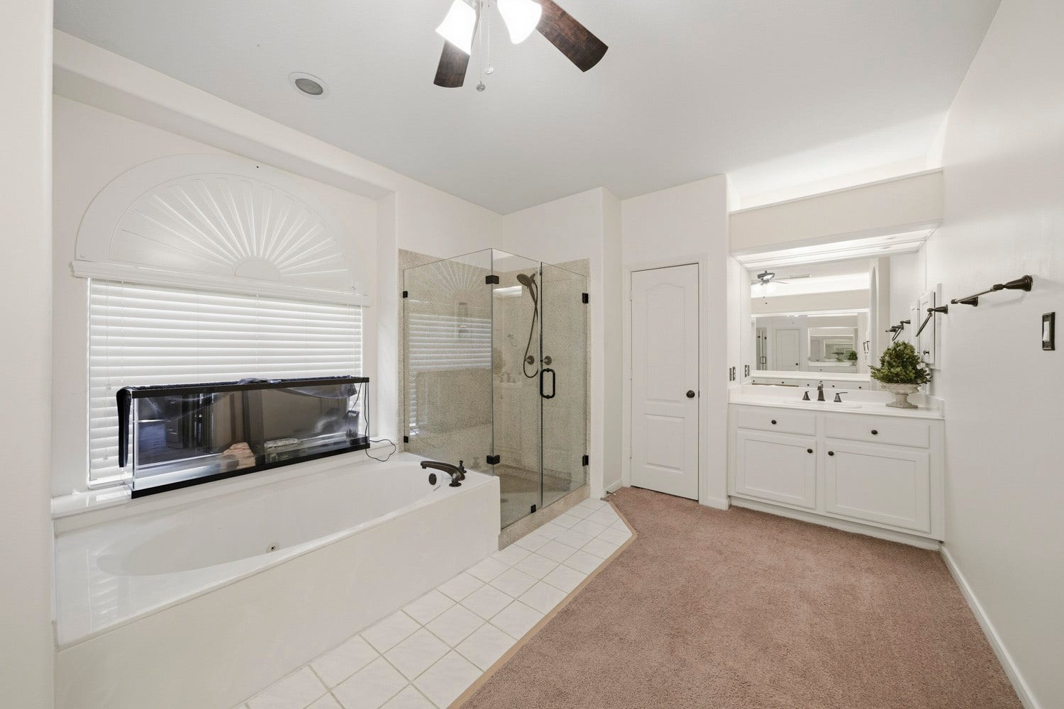 16 Fosters Court, Sugar Land, TX 77479 This spacious primary bathroom offers a relaxing retreat with a large soaking tub positioned beneath a bright window, alongside a separate glass-enclosed walk-in shower.