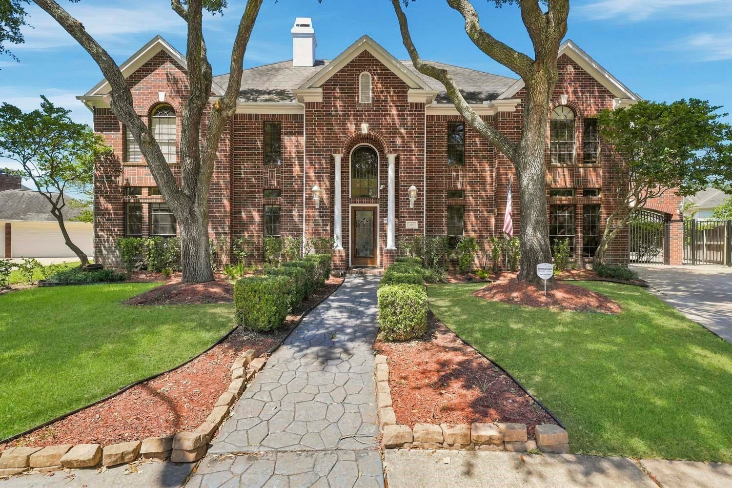 16 Fosters Court, Sugar Land, TX 77479 A stone walkway leads to the grand arched entry framed by classic columns and soaring windows.