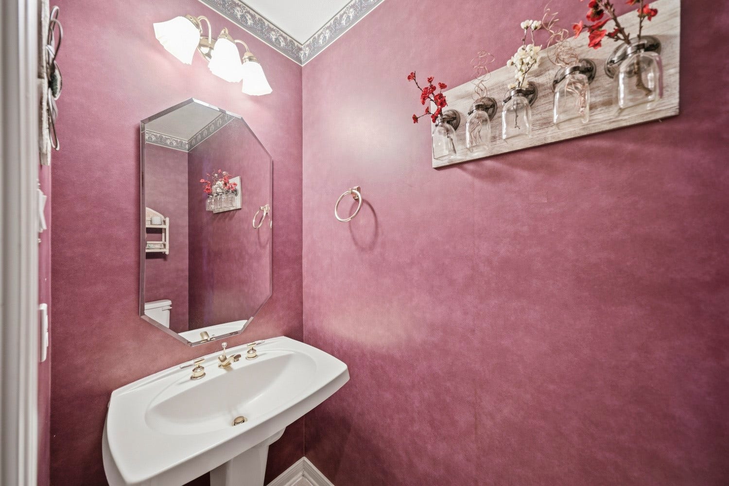 16 Fosters Court, Sugar Land, TX 77479 This charming powder bathroom features rich textured walls, a classic white pedestal sink, and an oversized beveled mirror.