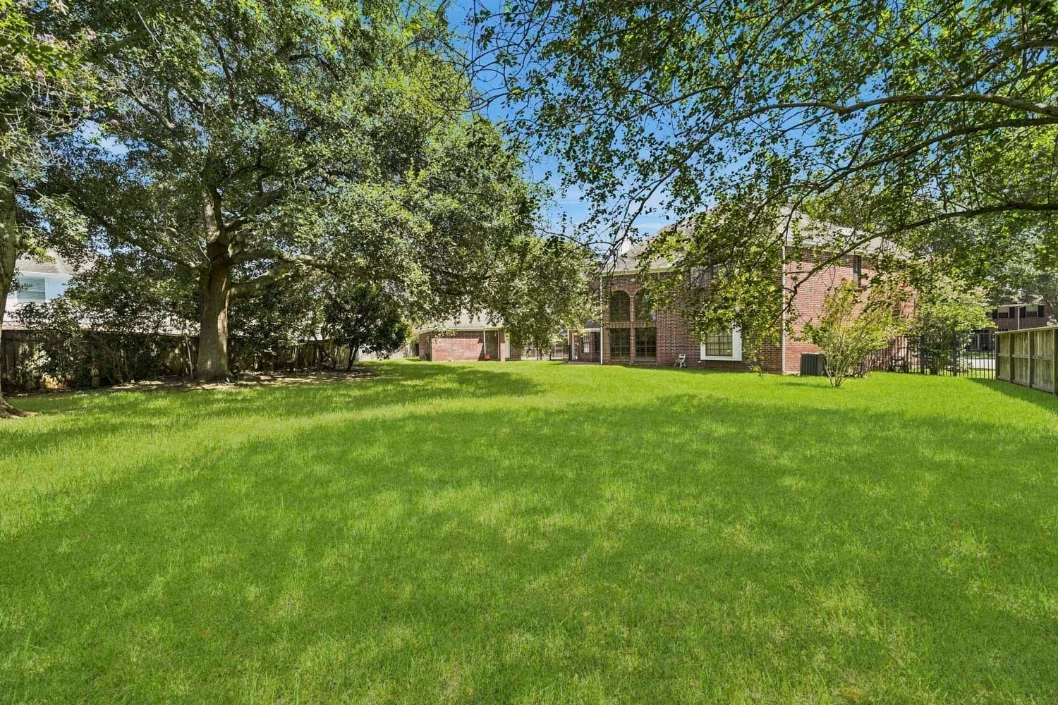 16 Fosters Court, Sugar Land, TX 77479 This expansive backyard offers a lush, open lawn surrounded by mature trees that provide abundant shade and a peaceful, private setting. The generous green space offers endless possibilities for outdoor entertaining, recreation, gardening, or creating a customized backyard retreat.