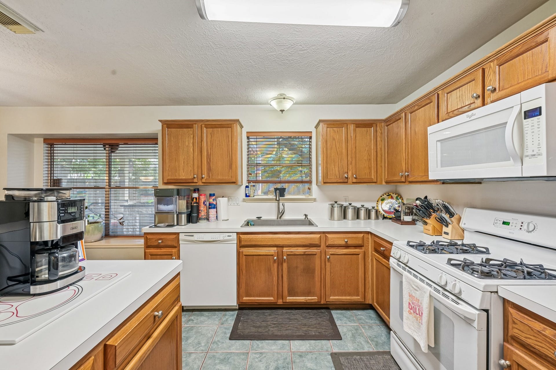 14219 Cypress Ridge Drive, Cypress, TX 77429 Spacious kitchen featuring solid wood cabinetry, gas cooktop and oven range, tile flooring, and ample counter space with garden window view.