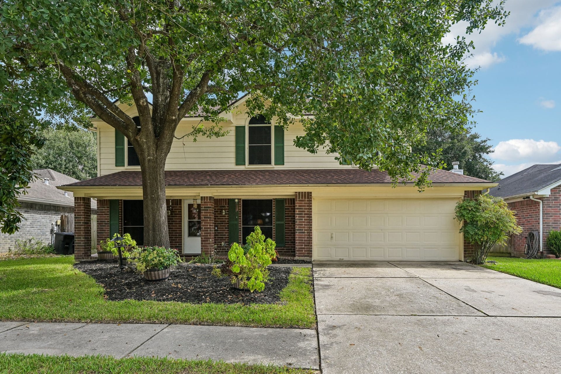 14219 Cypress Ridge Drive, Cypress, TX 77429 Classic two-story home featuring timeless brick and siding exterior, lush green lawn, mature shade tree, and an attached two-car garage.
