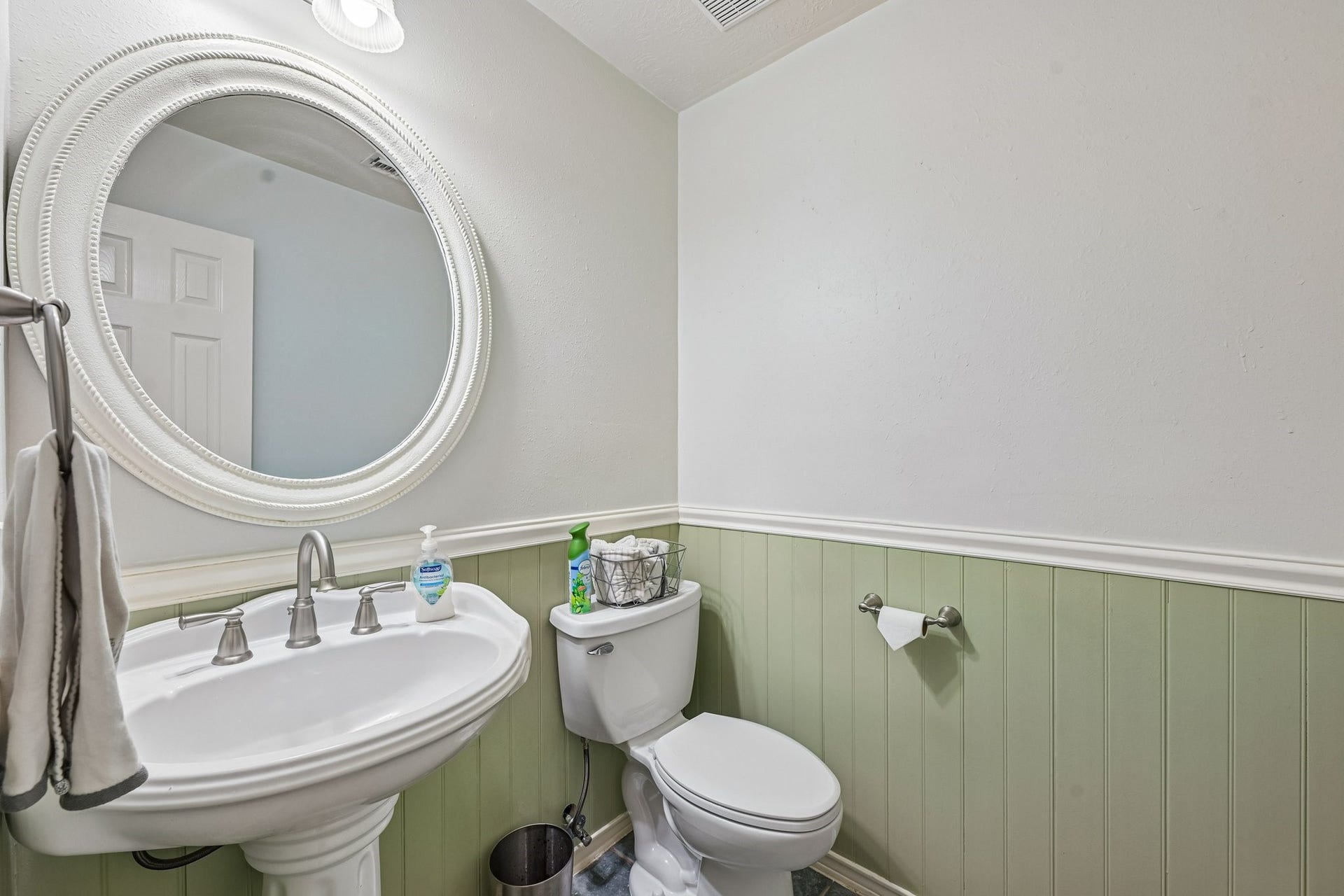 14219 Cypress Ridge Drive, Cypress, TX 77429 Downstairs half bath featuring classic sage green wainscoting, white pedestal sink, and decorative oval mirror.