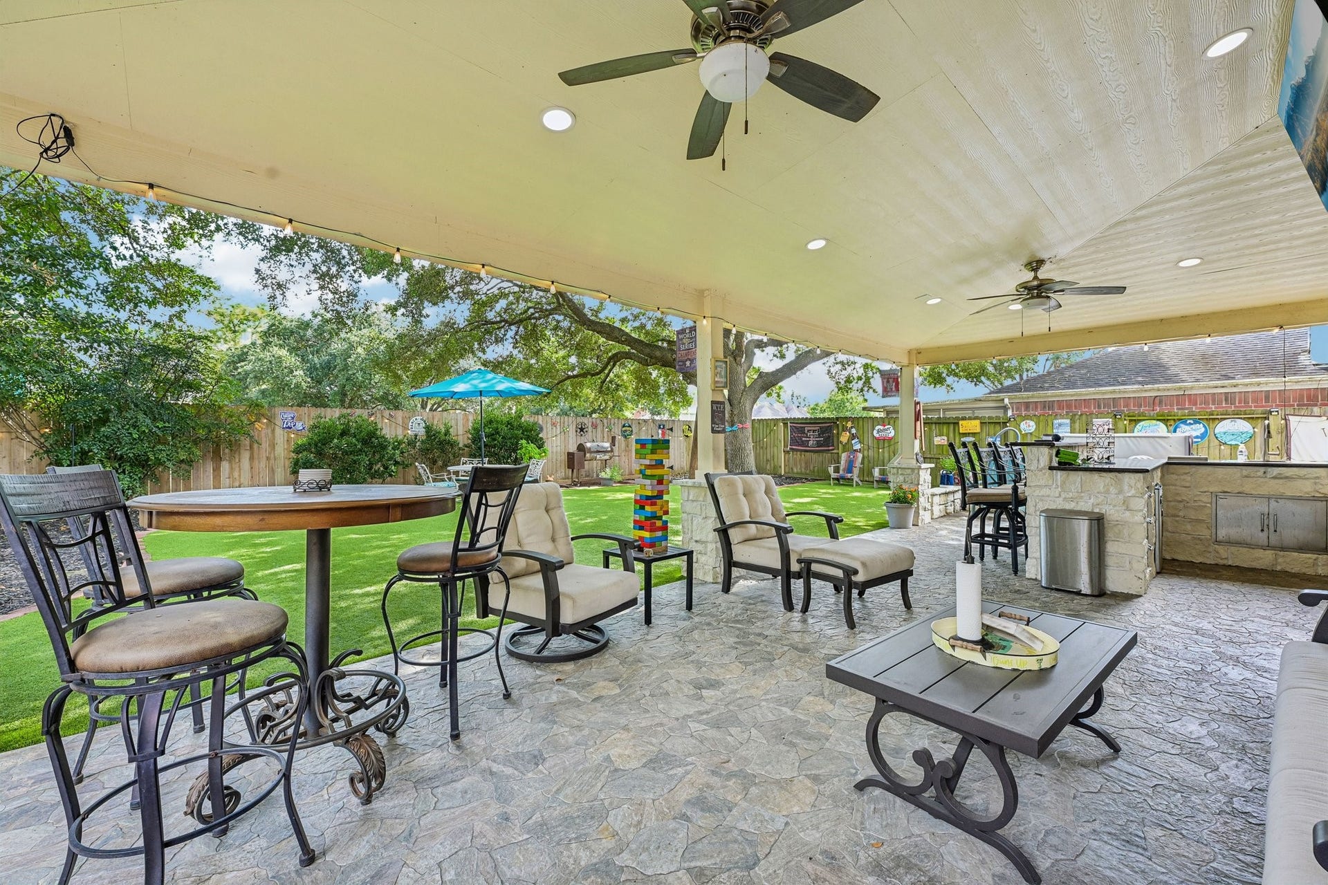 14219 Cypress Ridge Drive, Cypress, TX 77429 Impressive covered patio featuring stamped stone-look flooring, dual ceiling fans, recessed lighting, outdoor bar seating, and outdoor kitchen access.