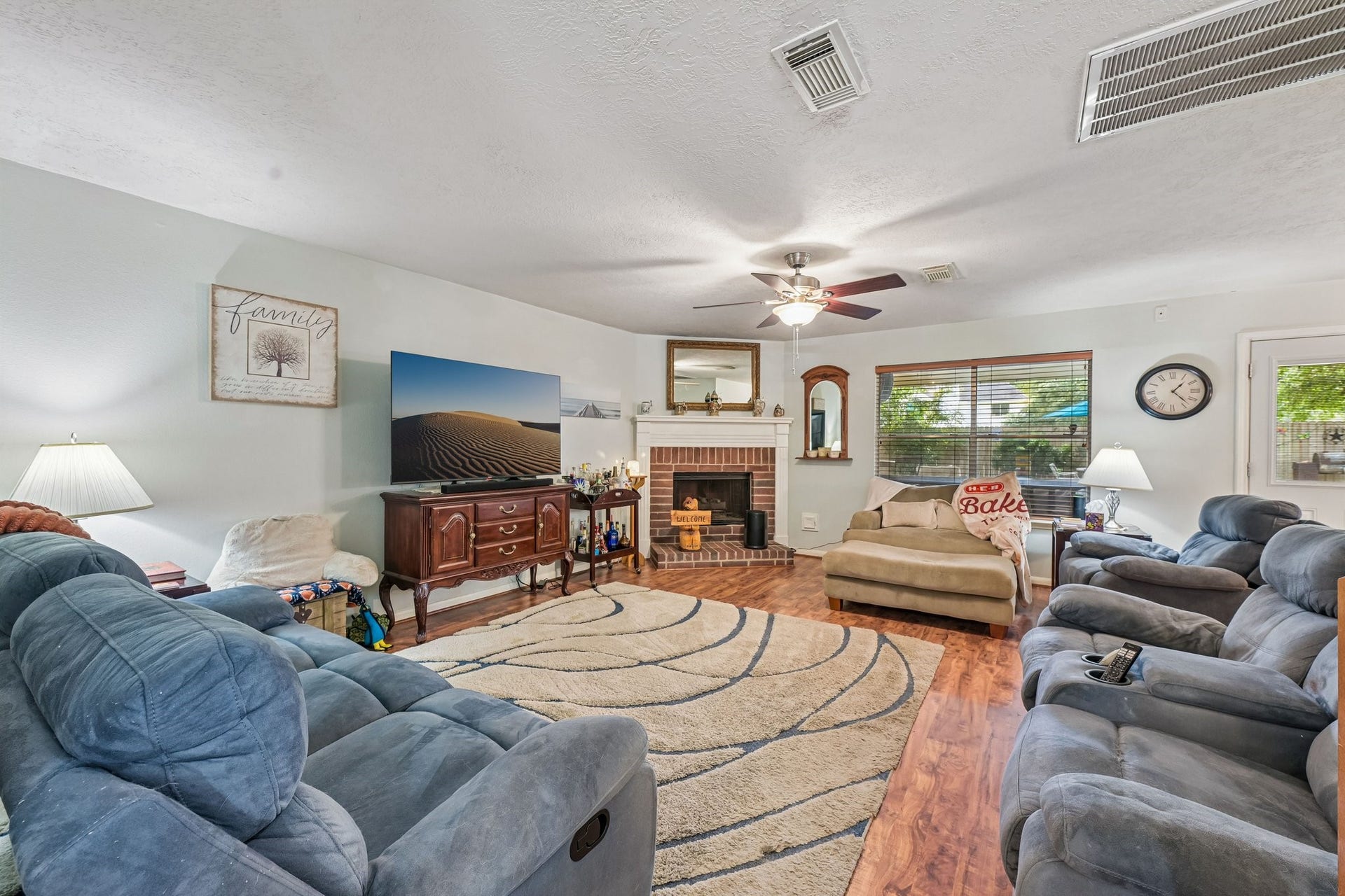 14219 Cypress Ridge Drive, Cypress, TX 77429 Expansive living room with wood-look flooring, ceiling fan, natural lighting, and a focal-point brick fireplace.