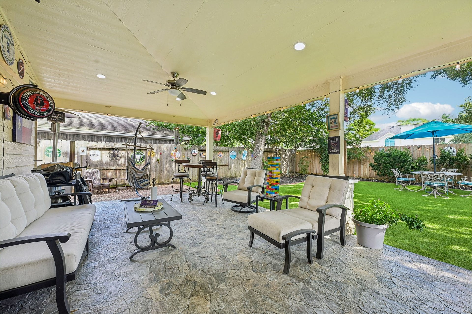 14219 Cypress Ridge Drive, Cypress, TX 77429 Generous covered lounge area offering comfortable outdoor sofa seating, coffee table, ceiling fan, and seamless connection to the backyard turf and green space.