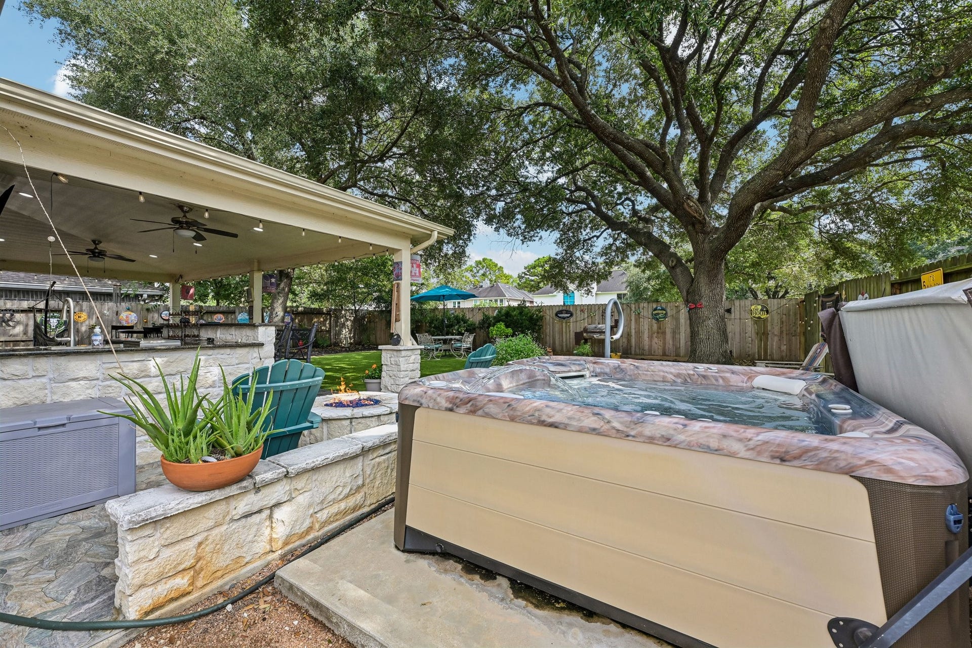14219 Cypress Ridge Drive, Cypress, TX 77429 Premium 2022 Hot Spring Vanguard hot tub set on a dedicated concrete pad adjacent to the stone fire pit and covered patio