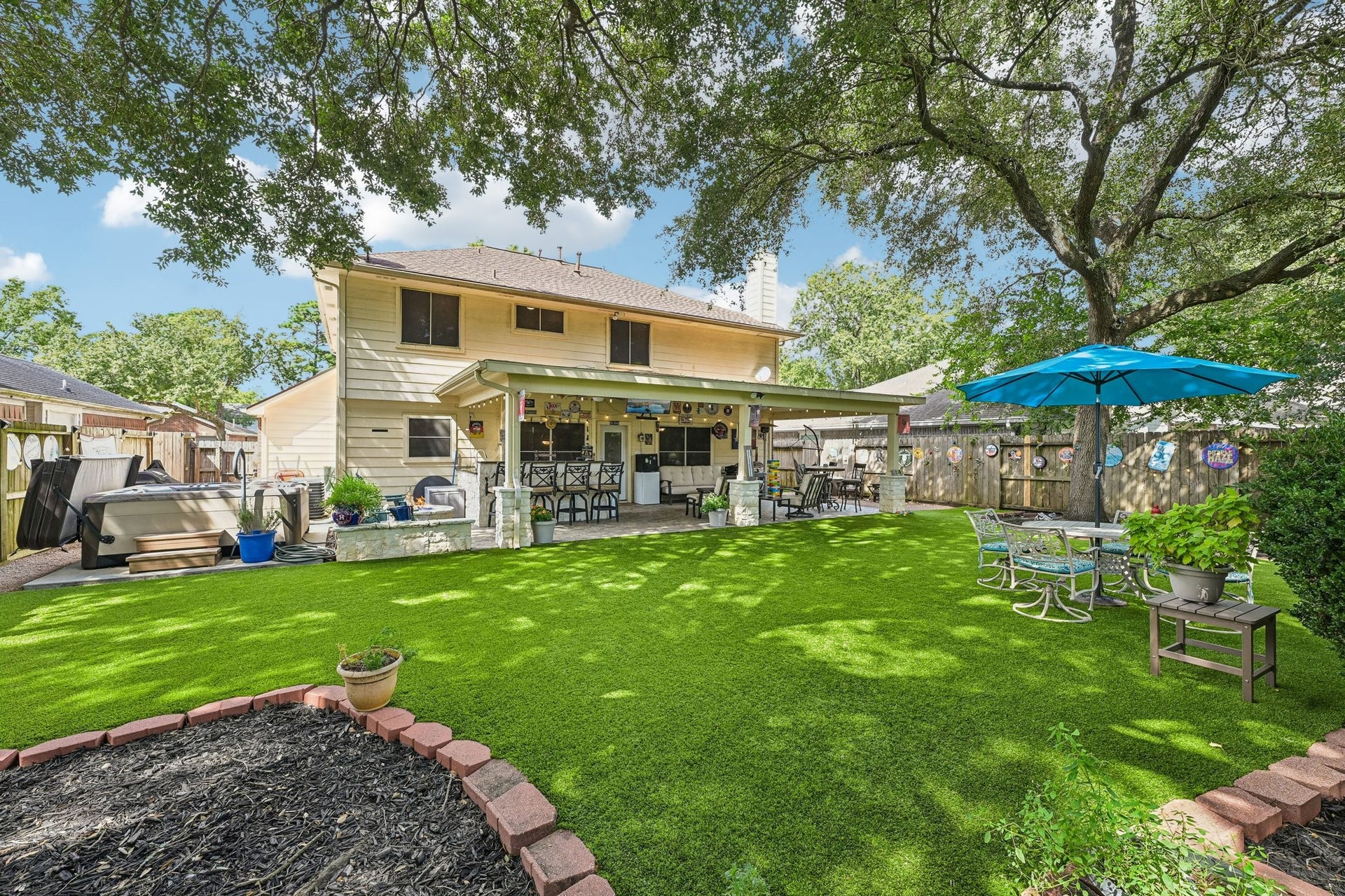 14219 Cypress Ridge Drive, Cypress, TX 77429 Overview of the ultimate backyard oasis showcasing the extensive covered patio, lush artificial turf lawn, custom putting green, and mature shade trees.