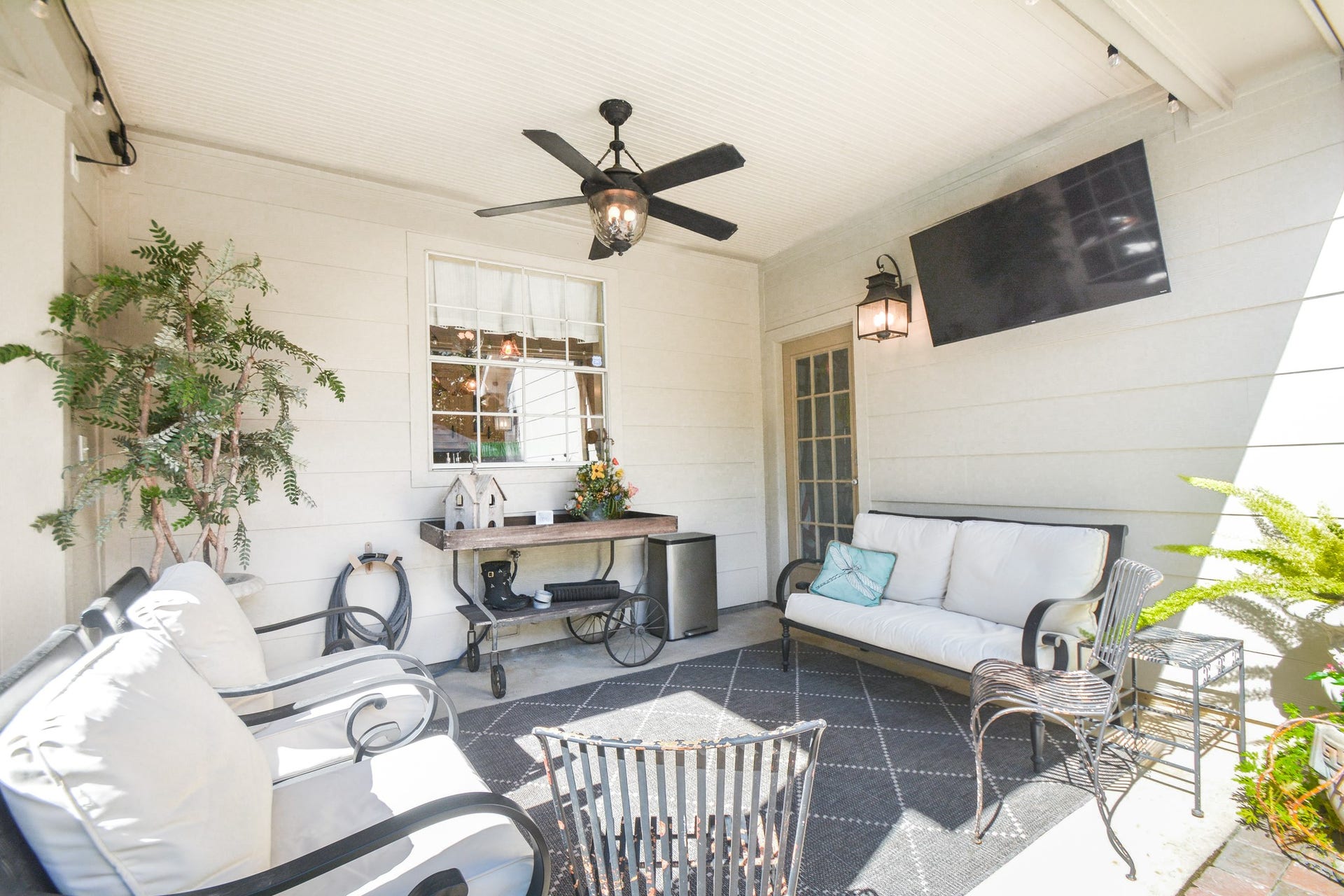 The covered poolside patio offers a comfortable outdoor gathering space with a ceiling fan and views of the pool.