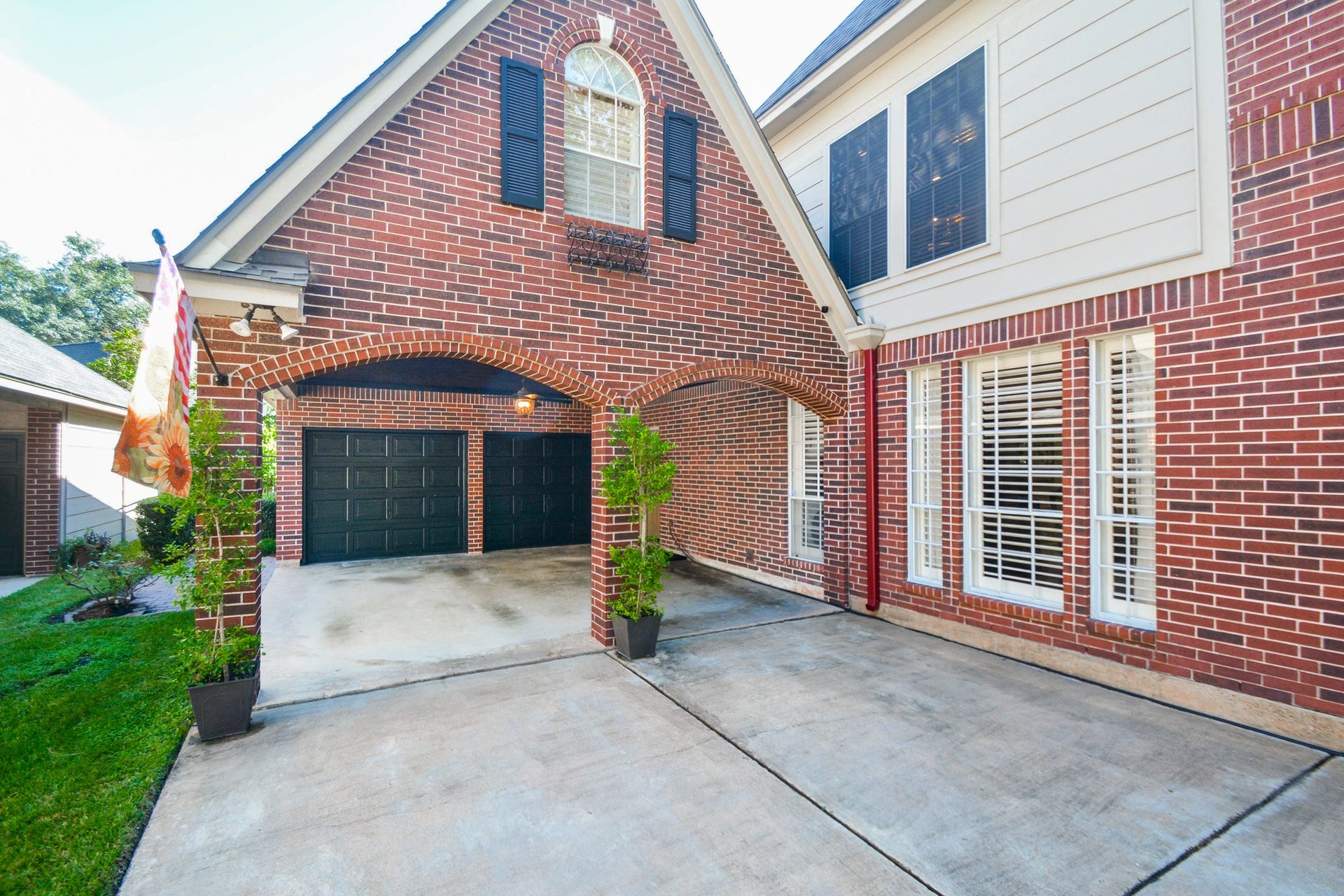 A stylish arched brick carport provides a covered arrival area beside the home.