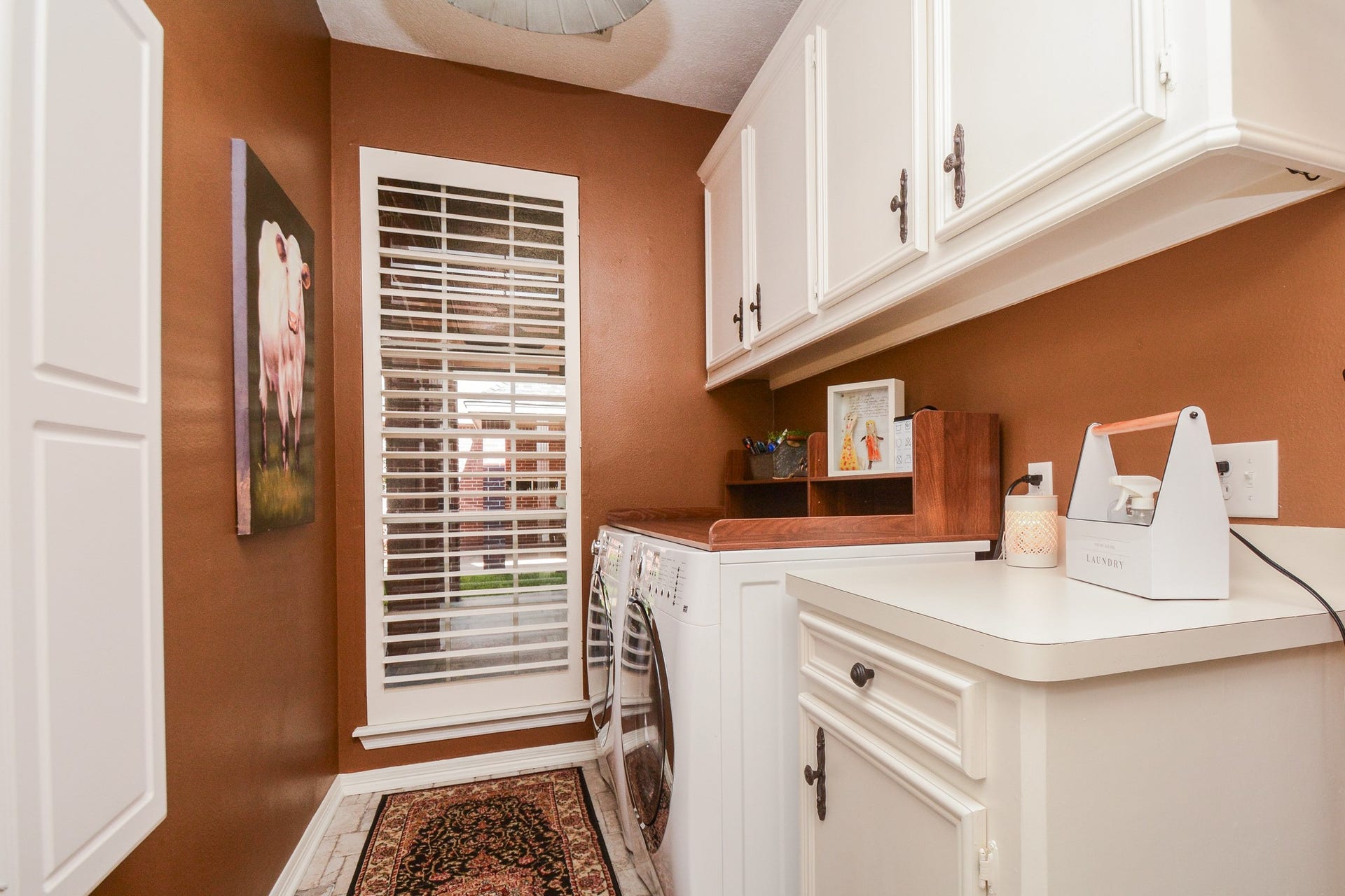 The first-floor laundry room features a generous countertop, upper and lower cabinetry, and natural light.