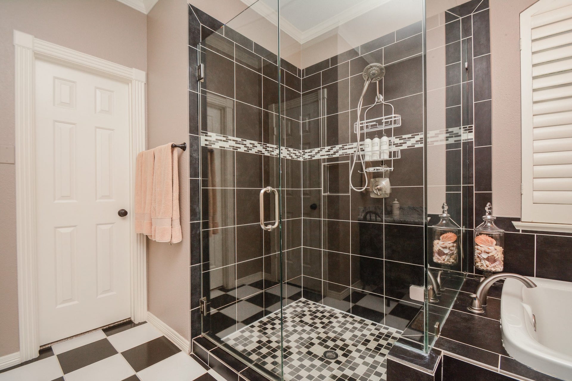 The glass-enclosed shower features contrasting tile accents beside the primary bathrooms soaking tub.