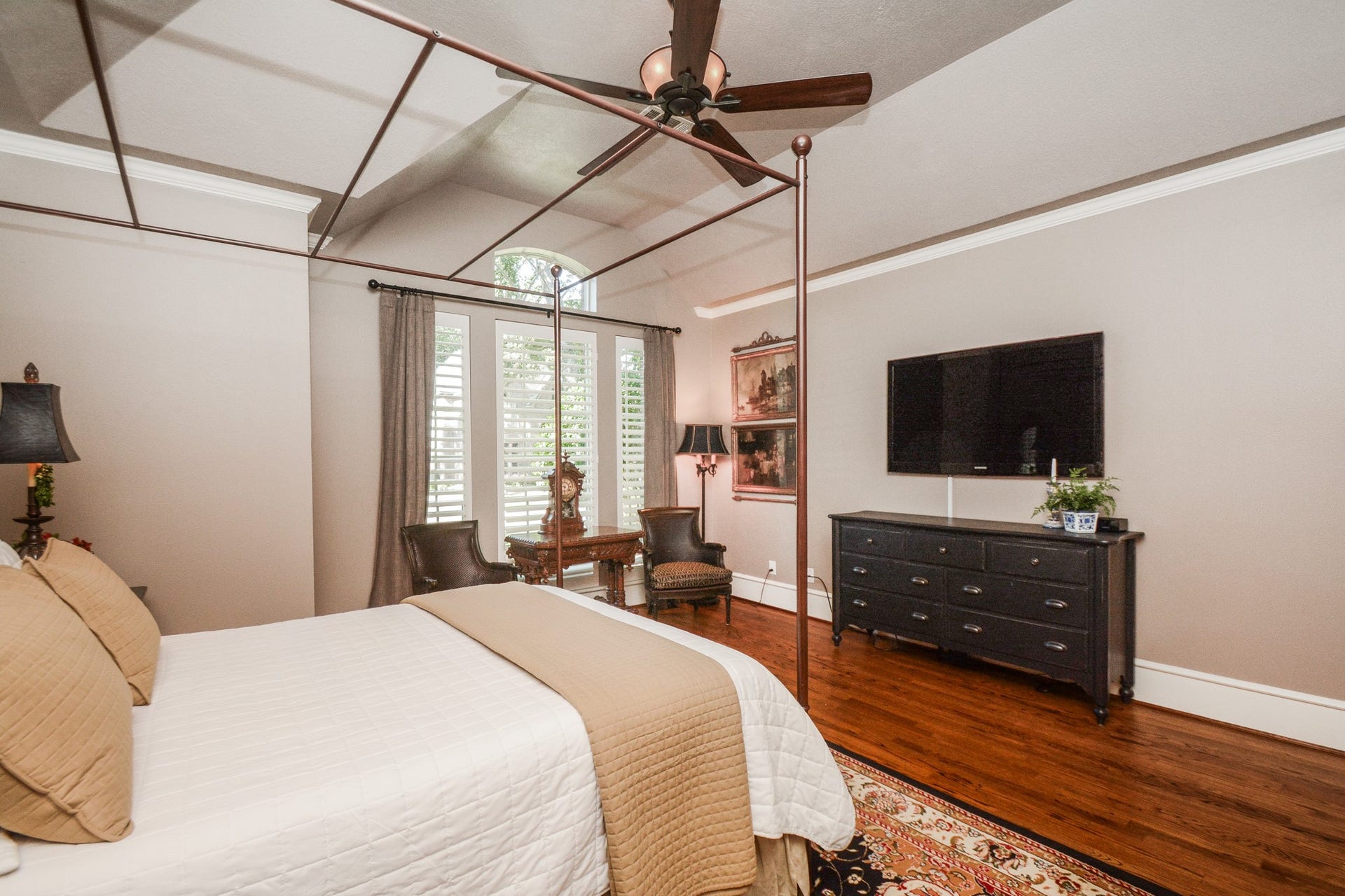 Hardwood floors and generous windows bring warmth and natural light to the spacious primary bedroom.