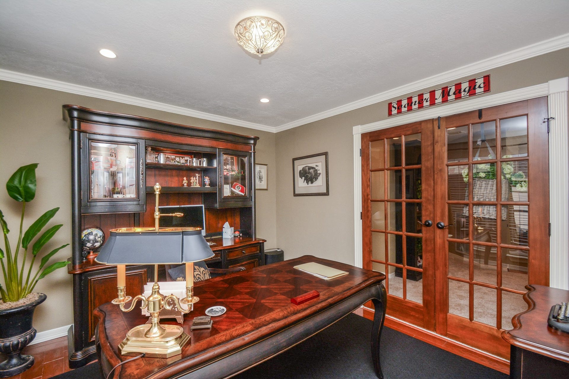 Glass French doors lead into the inviting upstairs home office, featuring coordinating wood cabinetry and display shelving.