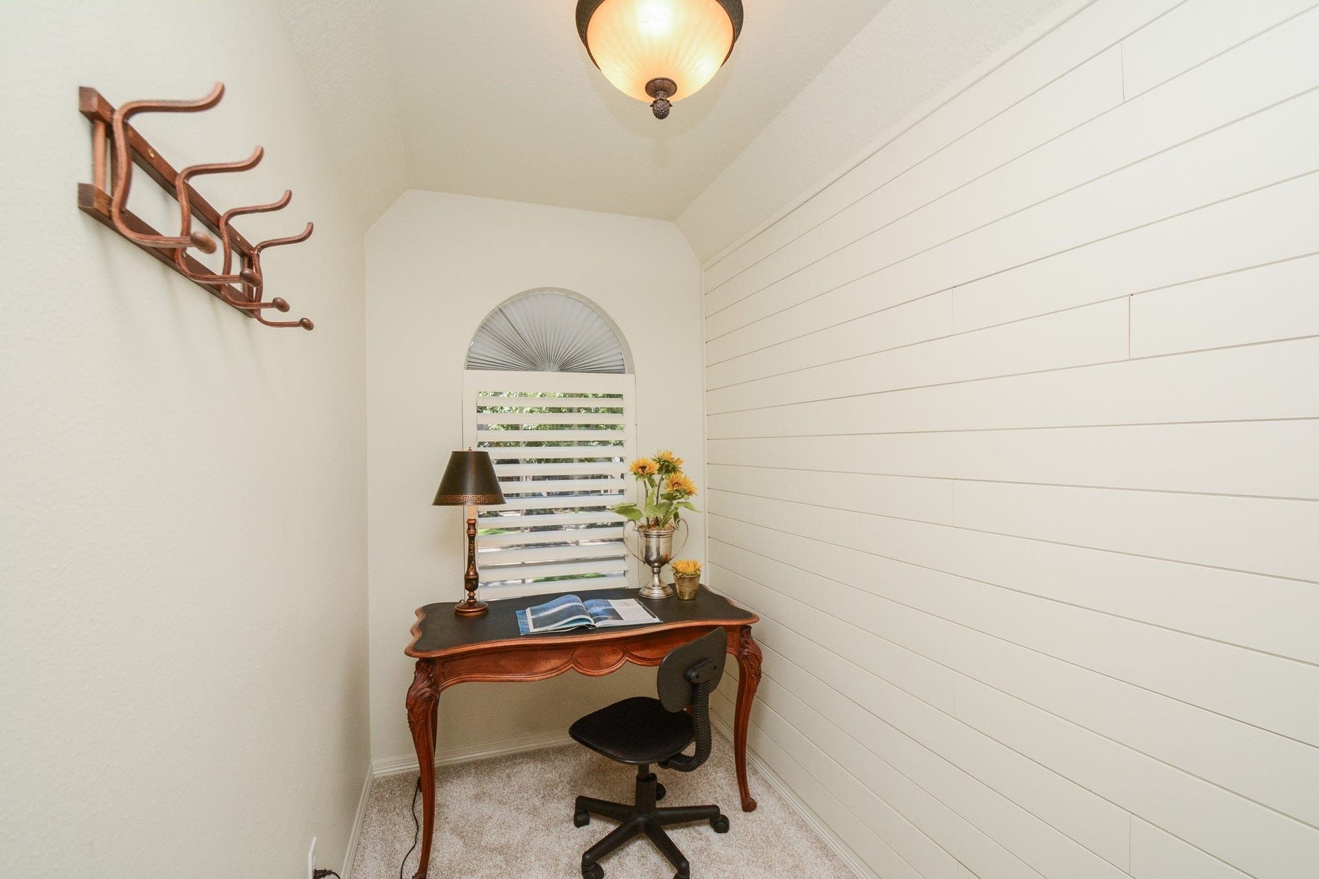 A tucked-away desk nook with an arched window provides a convenient spot for studying or working at home.