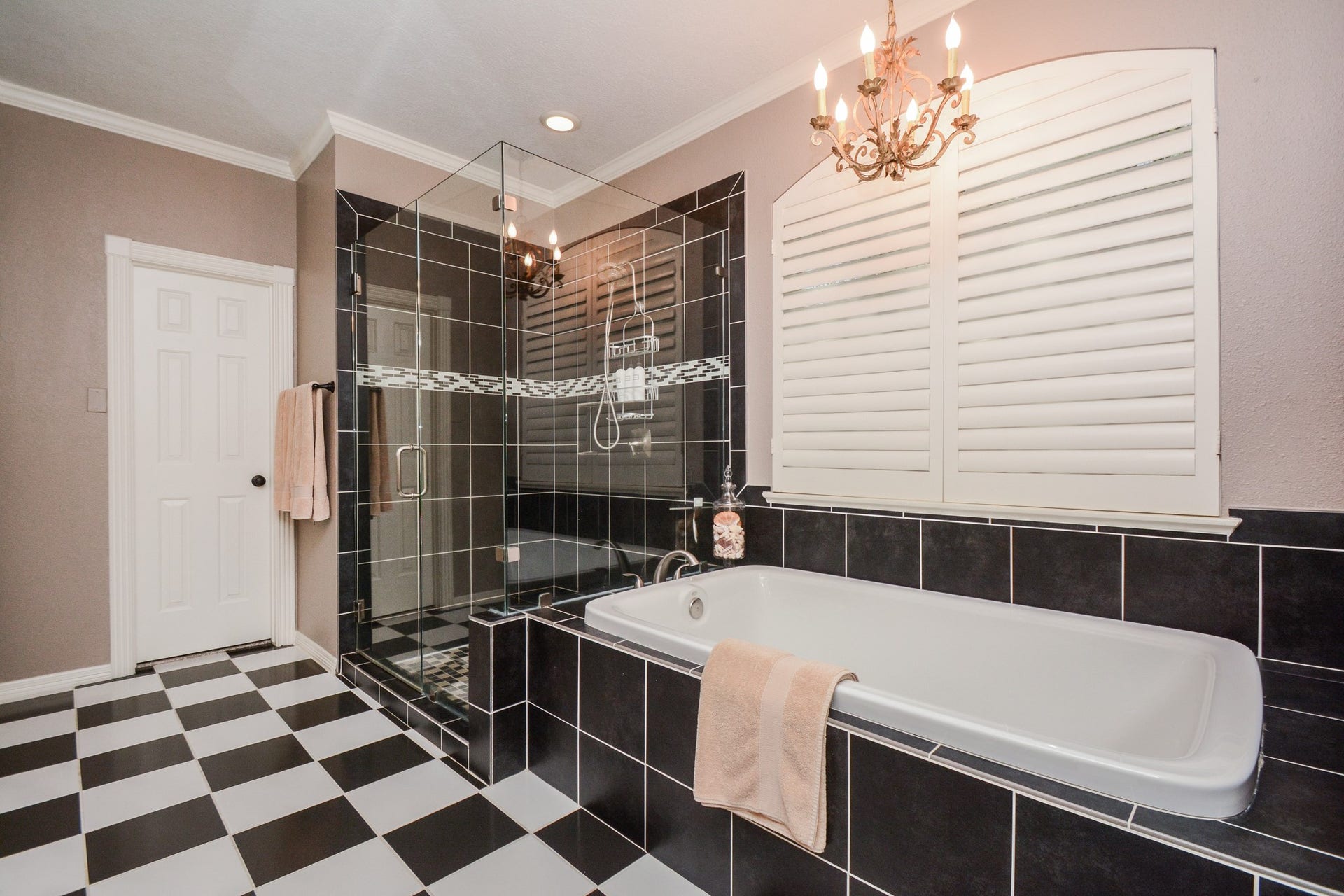 A soaking tub, separate glass-enclosed shower, and chandelier create a relaxing primary bathroom retreat.