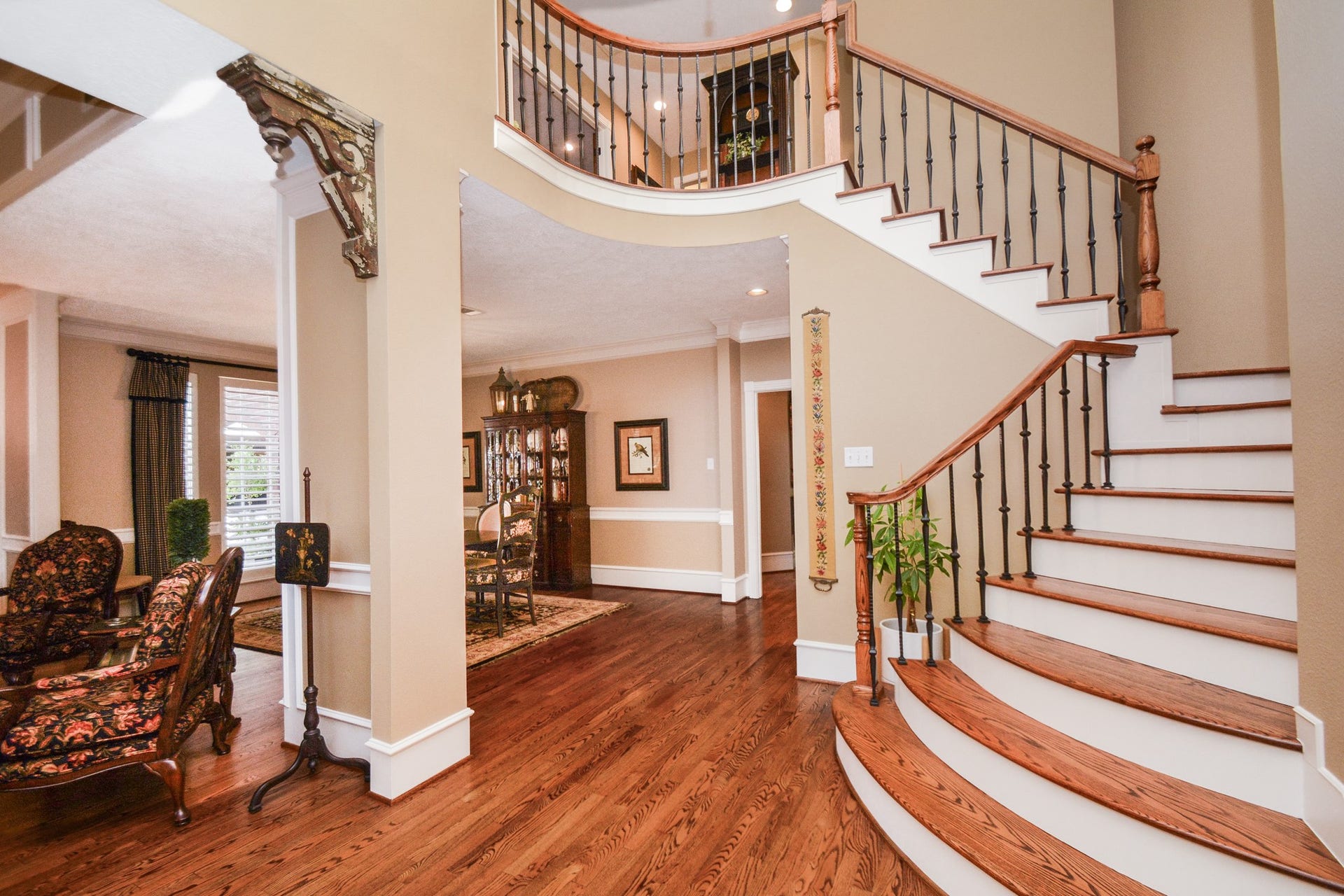 A graceful curved staircase with wood treads and decorative iron balusters makes a striking impression above the hardwood floors.