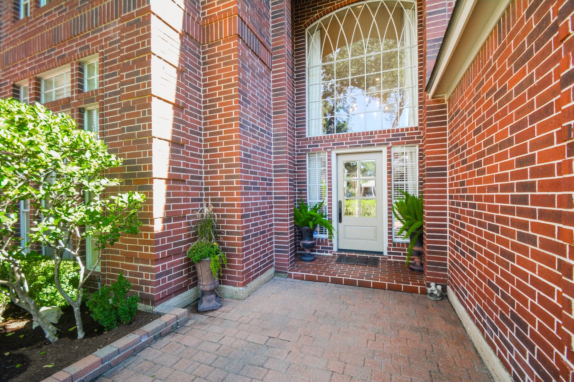 The sheltered front entry features a decorative glass door beneath a soaring arched window.