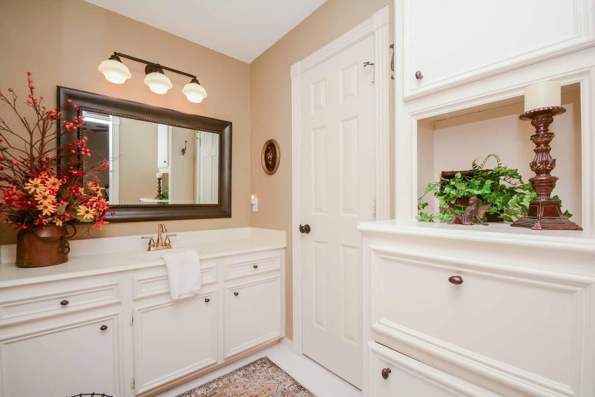 The upstairs bathroom vanity area offers white cabinetry, a generous countertop, and built-in storage with an open display shelf.