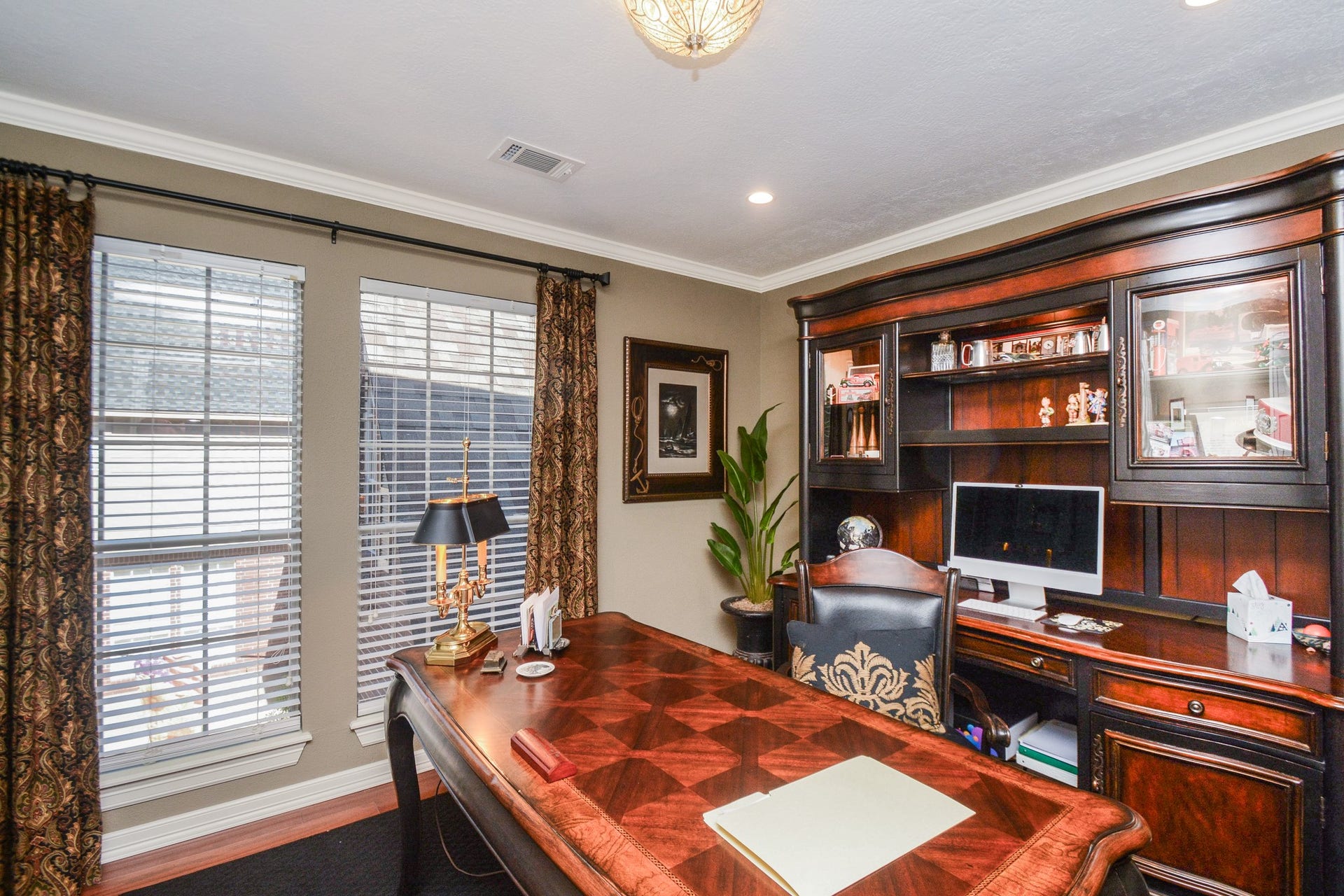 The upstairs home office features crown molding and large windows that fill the space with natural light, creating a comfortable, inviting workspace.
