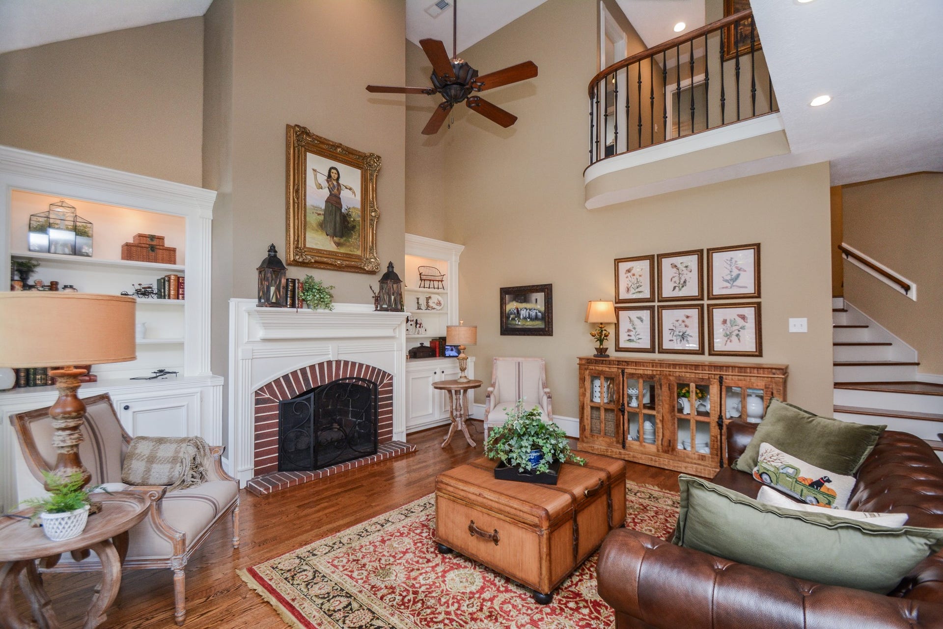 The family room combines soaring ceilings, hardwood floors, built-in shelving, and a fireplace with a classic brick surround.