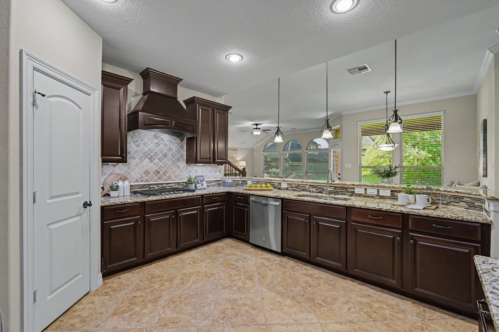 Gourmet kitchen with custom mahogany cabinetry, granite countertops, gas cooking w/hooded vent, stainless appliances