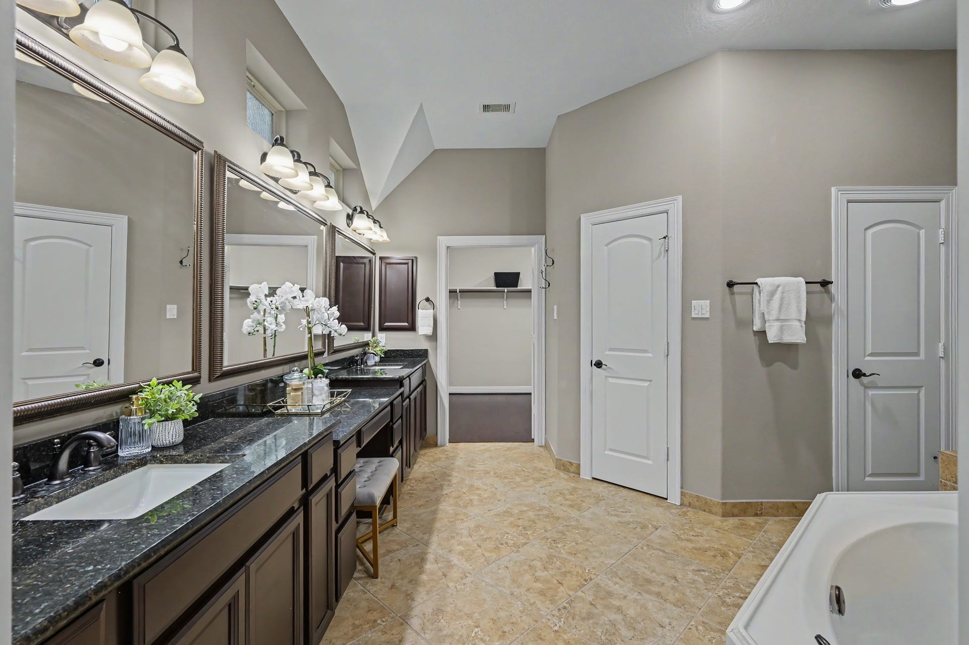 Primary bath boasts dual vanities with extened counter space, framed mirror and natural light from above.